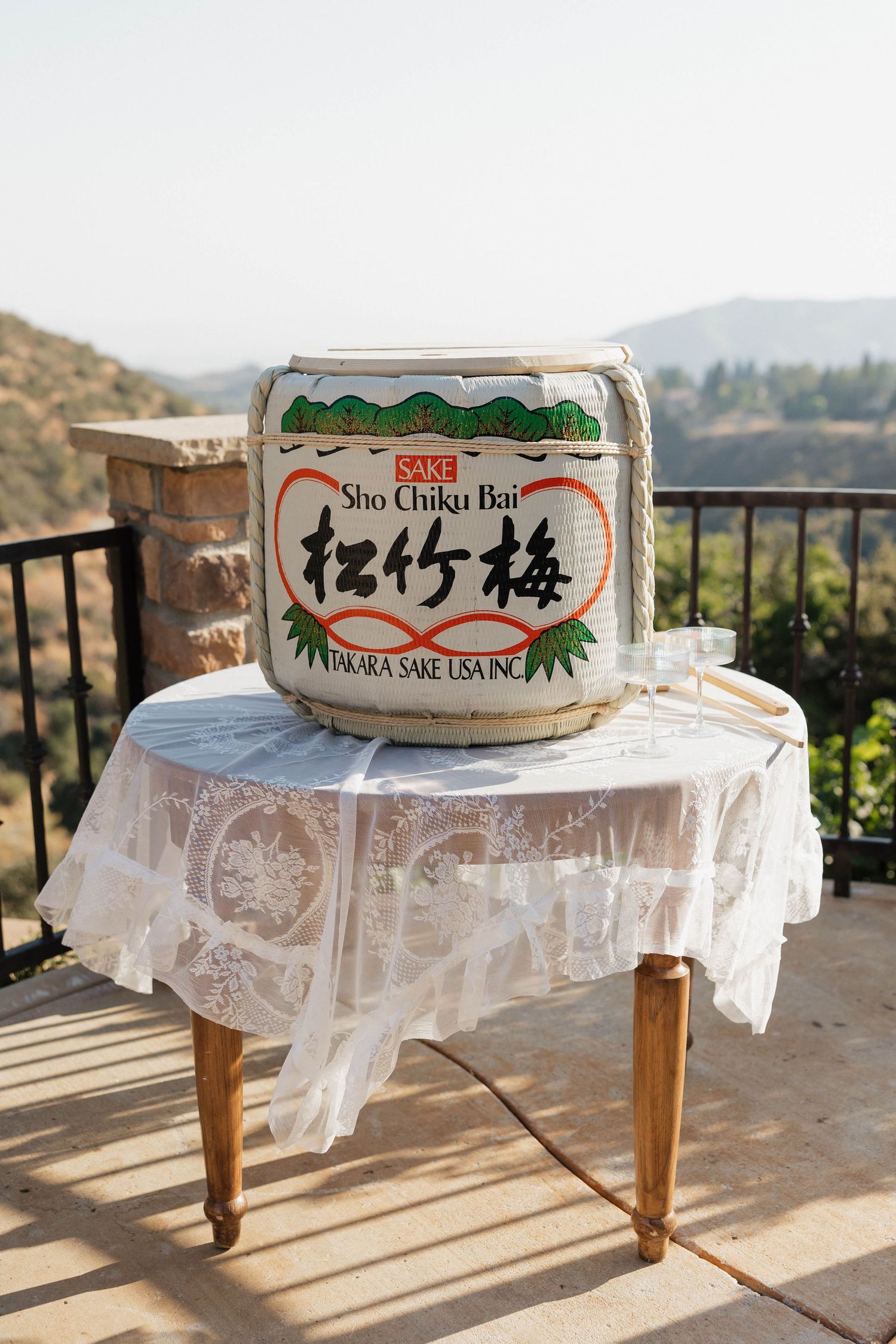 A traditional Sho Chiku Bai sake barrel displayed on a table with mountain views in the background.