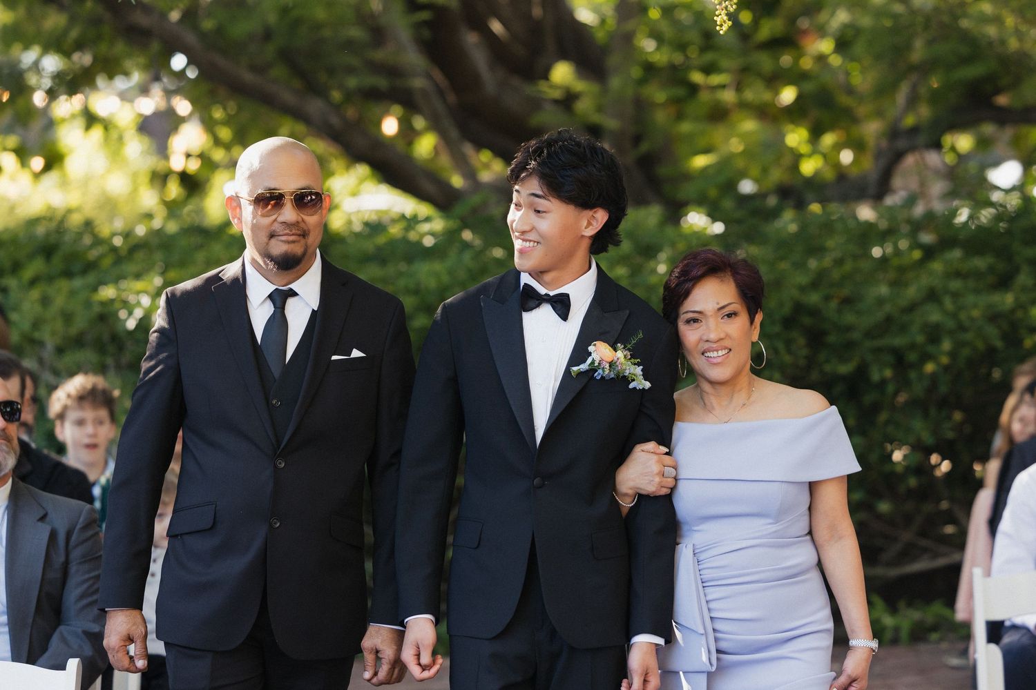 Wedding party gathered outdoors in formal attire for group photos.