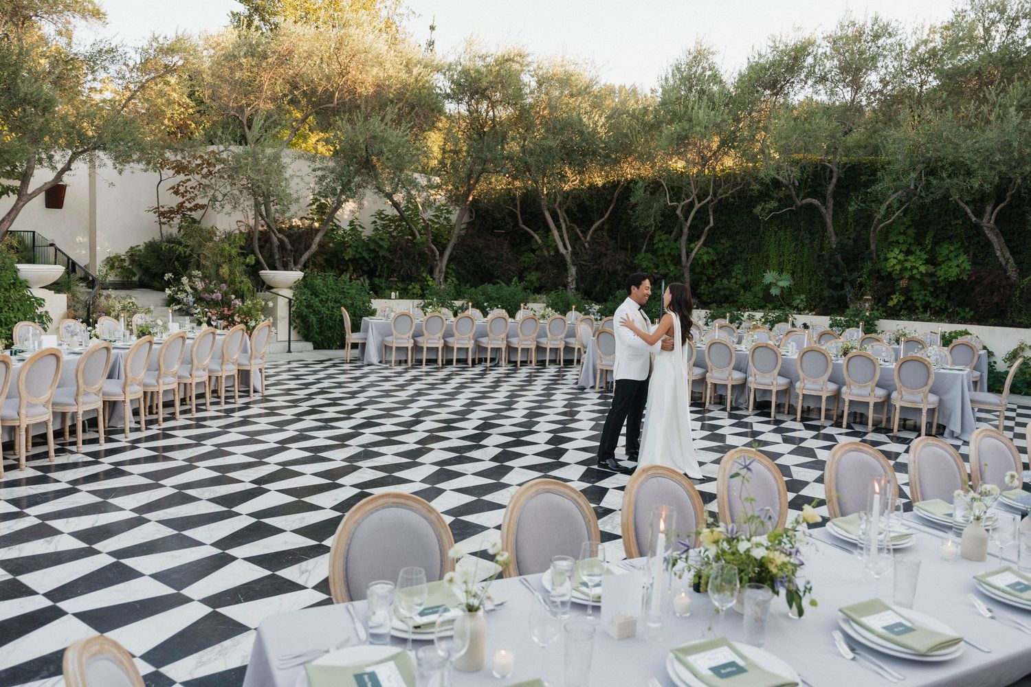 Elegant outdoor wedding reception setup with black and white checkered dance floor.