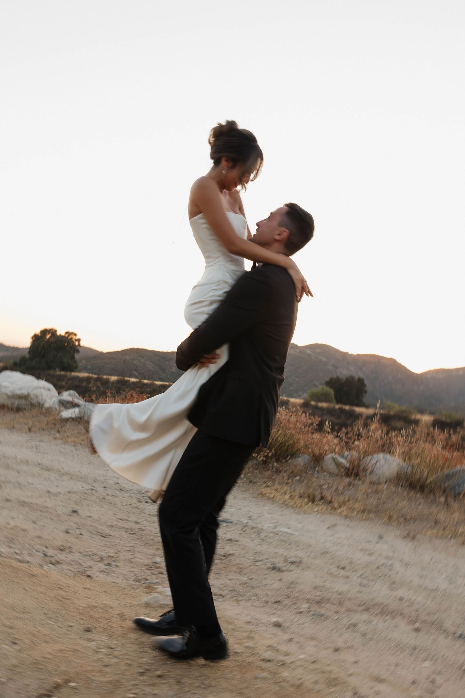 Romantic sunset lift pose during wedding photoshoot in nature.