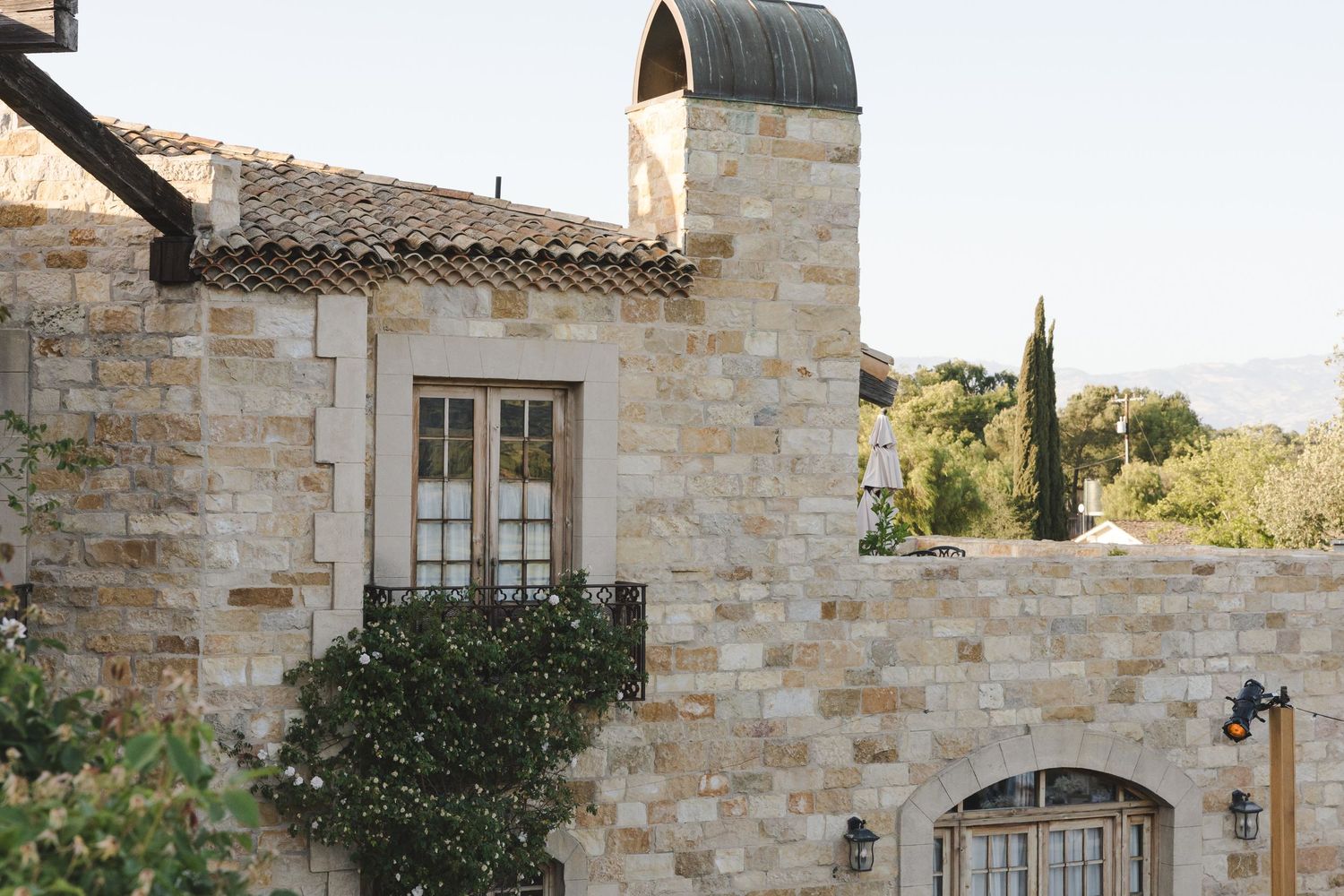 Mediterranean style stone villa with arched doorway and French windows showcasing traditional architectural details.