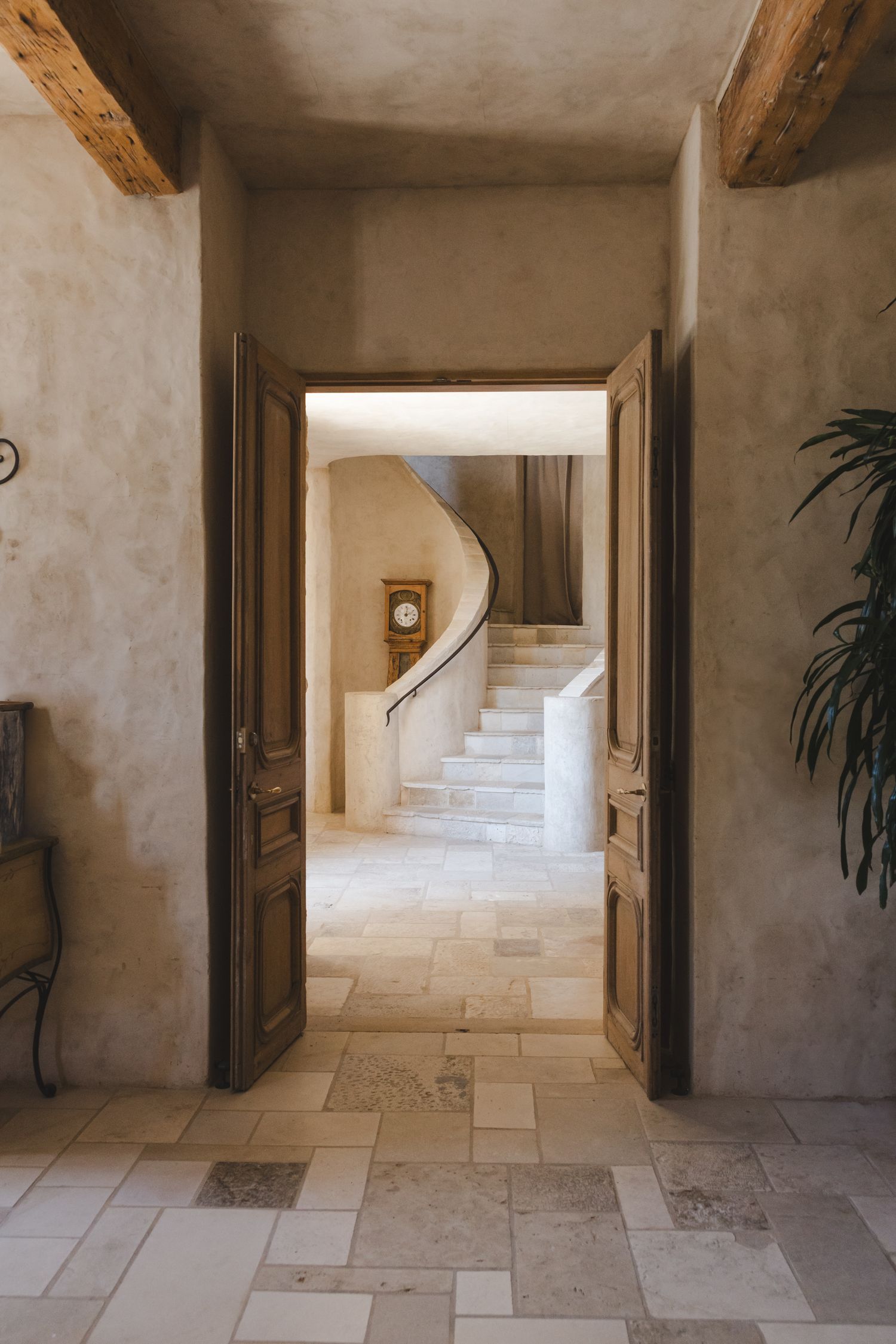 Rustic stone hallway with wooden beams and limestone flooring leading to a staircase.