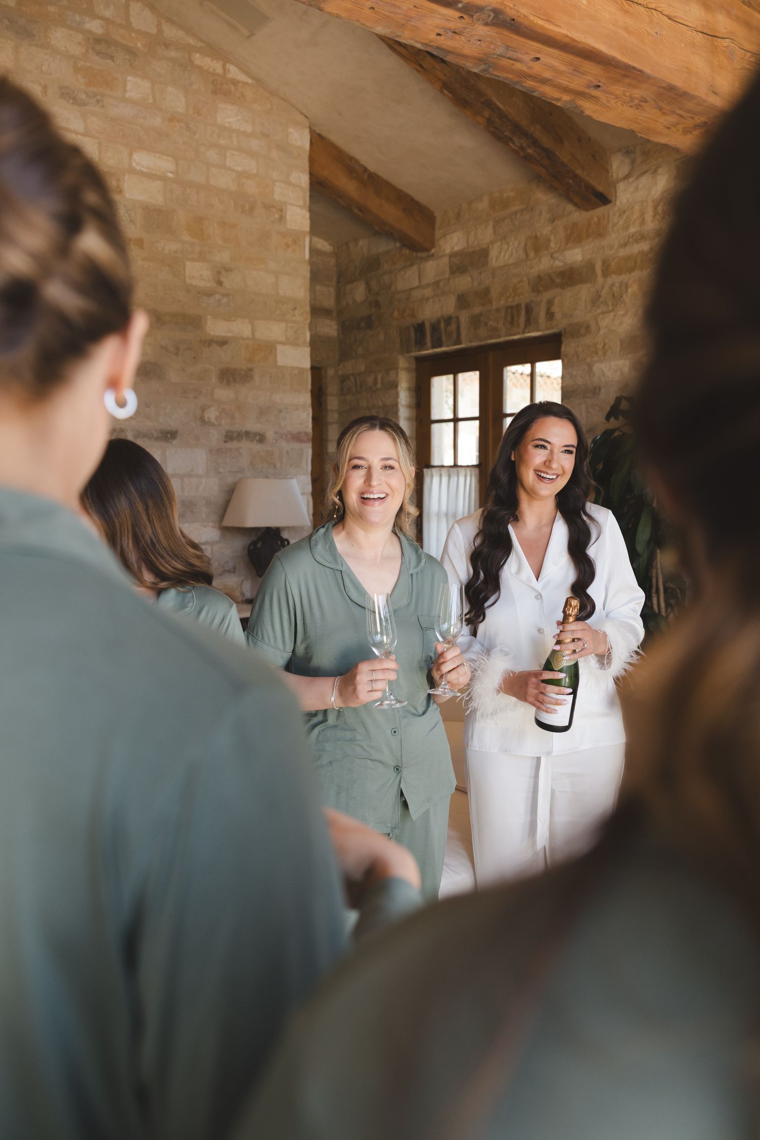 People gather for celebratory drinks in a rustic stone-walled room with exposed wooden beams.