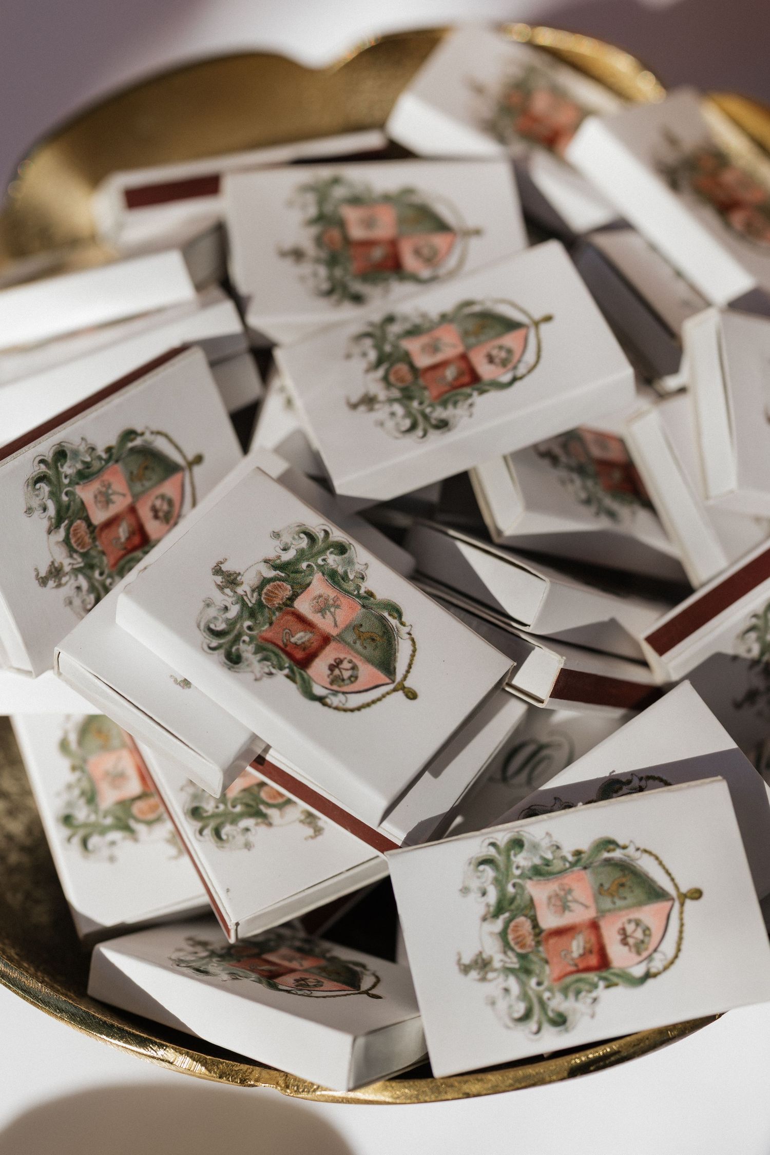 Custom heraldic crest matchbooks as wedding favors displayed in gold bowl.