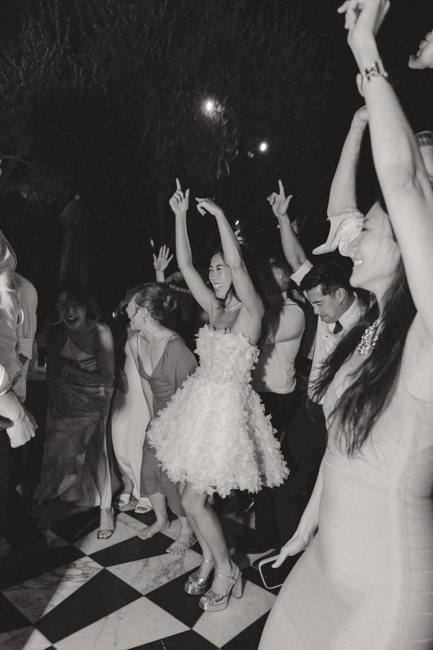 Wedding guests dancing and celebrating at a nighttime outdoor reception.