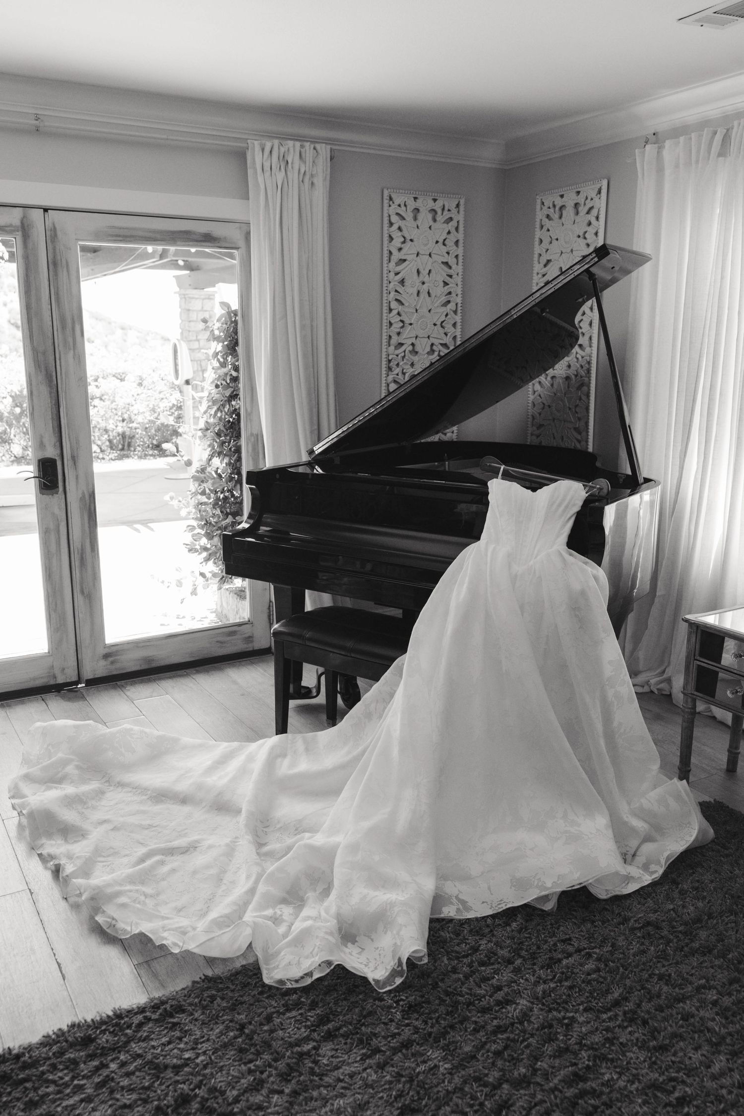 Black and white composition of a wedding dress elegantly draped near a grand piano.