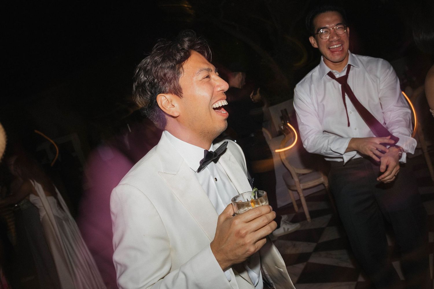 Wedding reception guests enjoying the evening celebration in dim lighting.