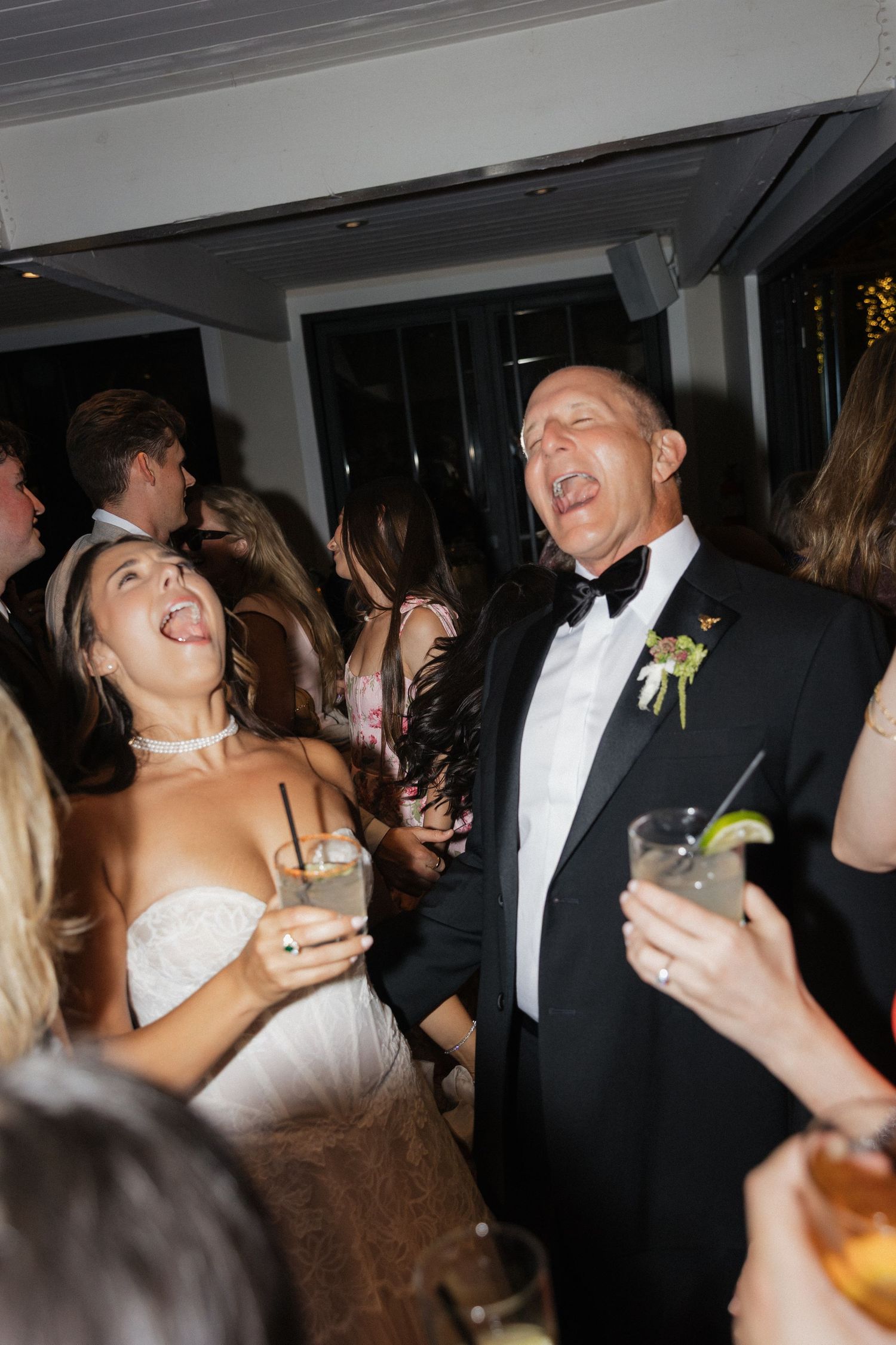Bride and older gentleman laugh together joyfully on the wedding reception dance floor.