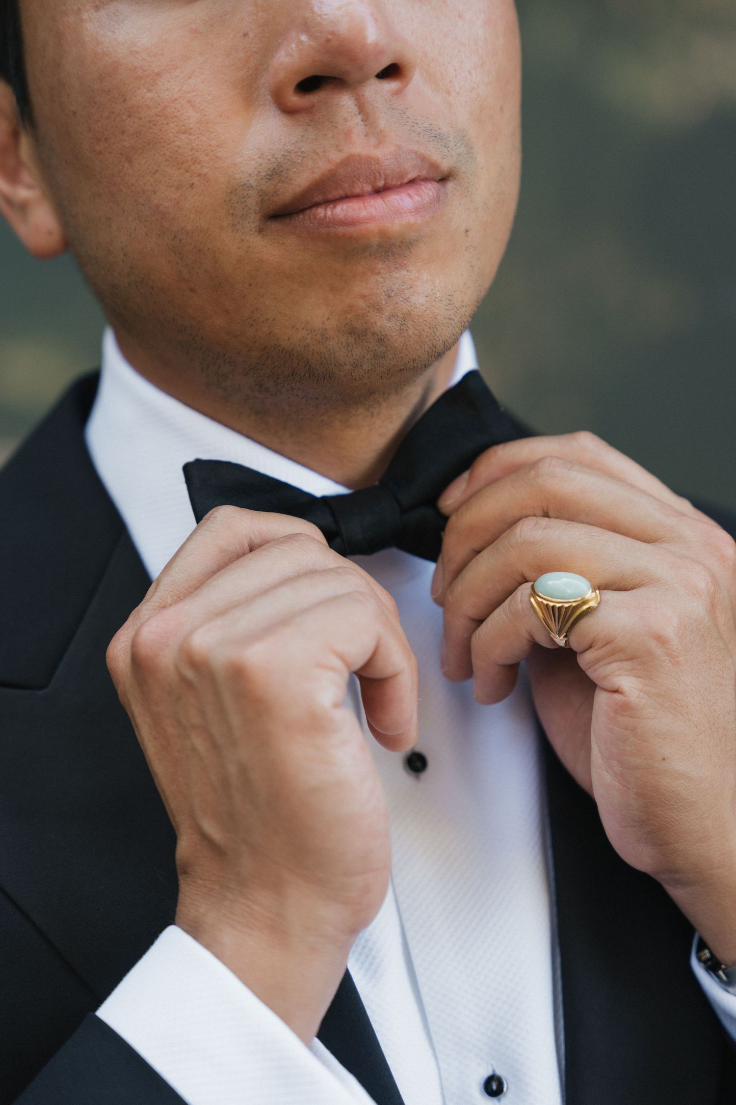 Close-up of hands adjusting a black bowtie on a formal tuxedo.