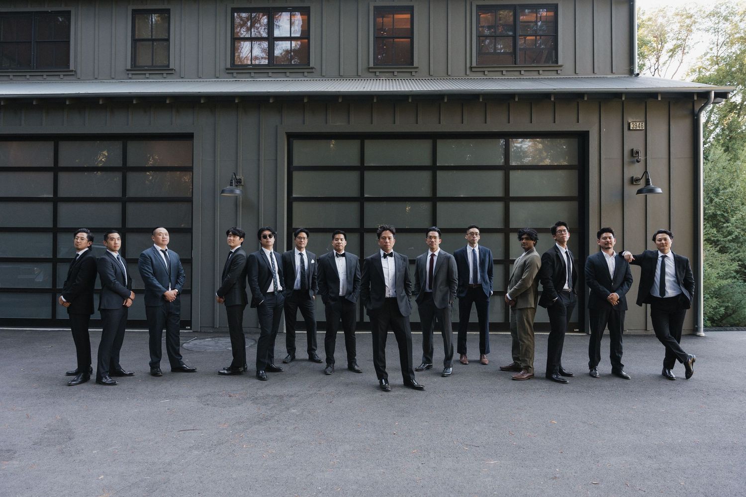 A line of formally dressed people standing in front of a modern gray building exterior.