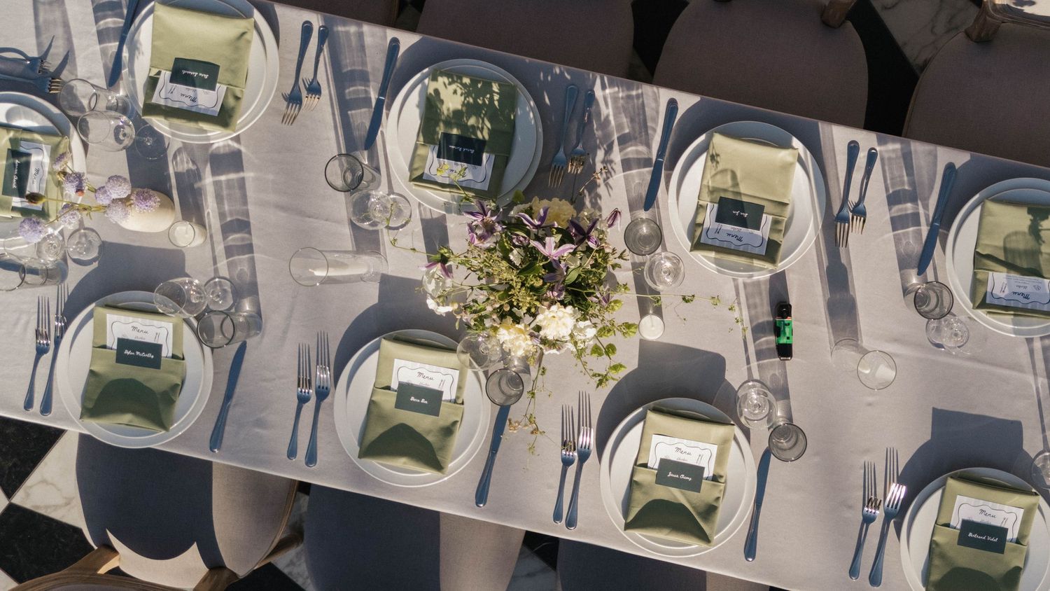 A series of elegant place settings at a formal wedding reception with white linens and gold accents.