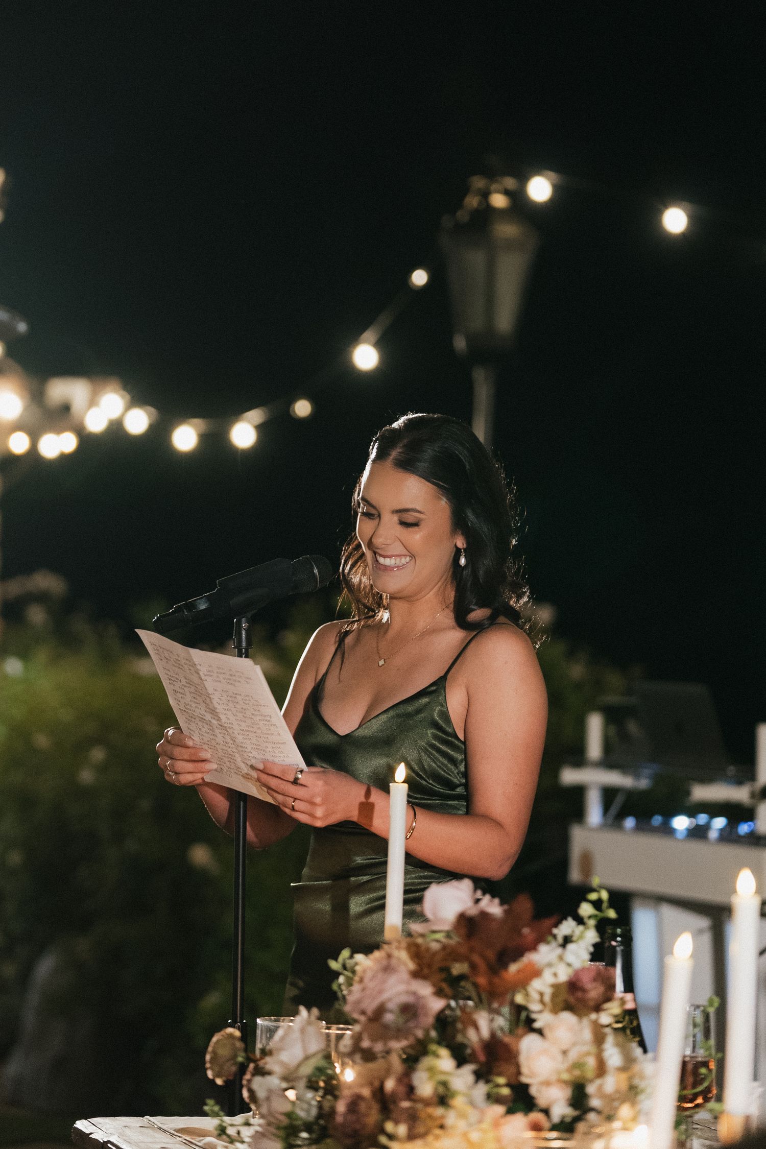 Wedding reception speech being delivered at night under outdoor lighting.