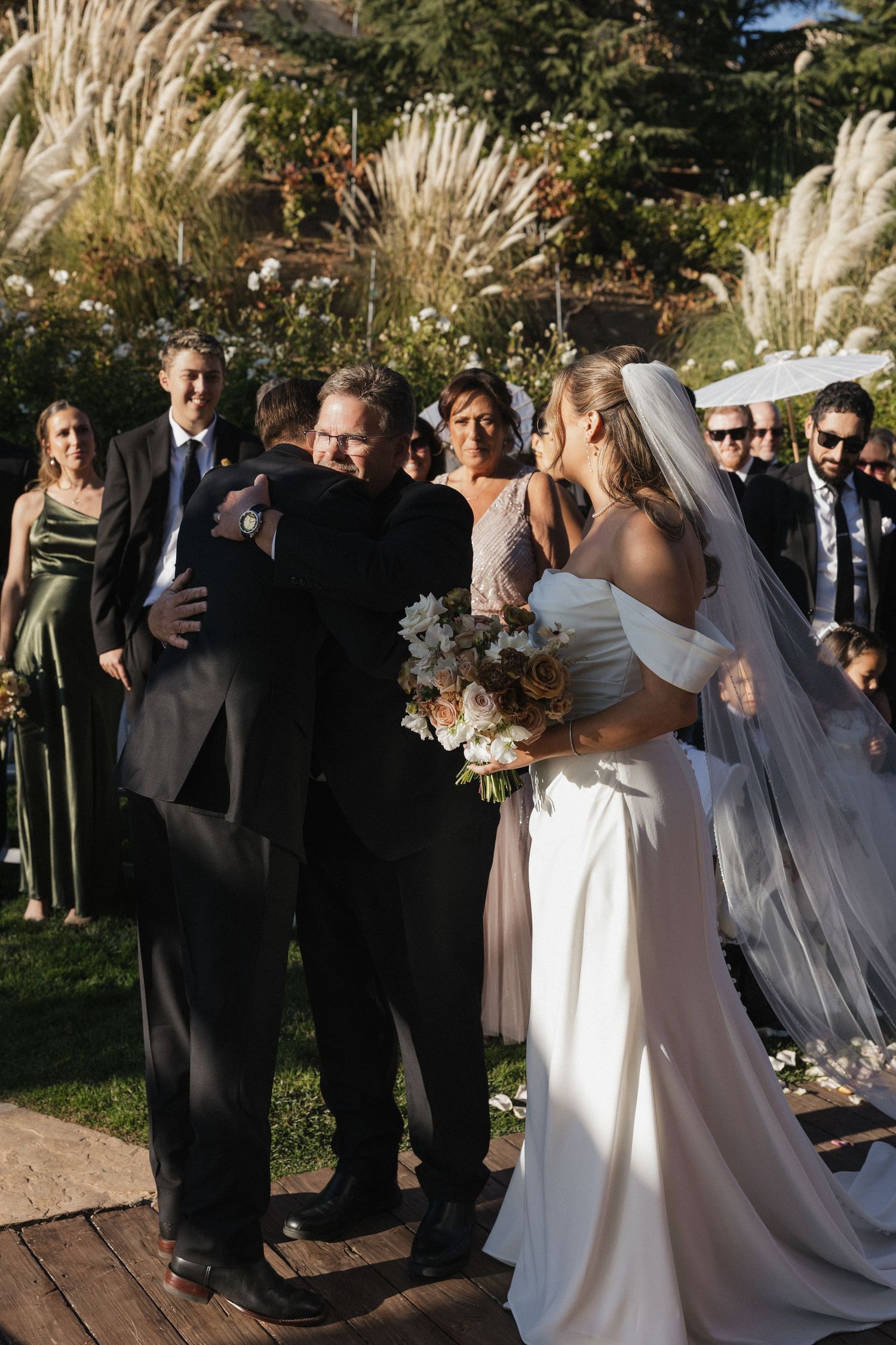 An outdoor wedding ceremony with pampas grass and floral decorations in a garden setting.