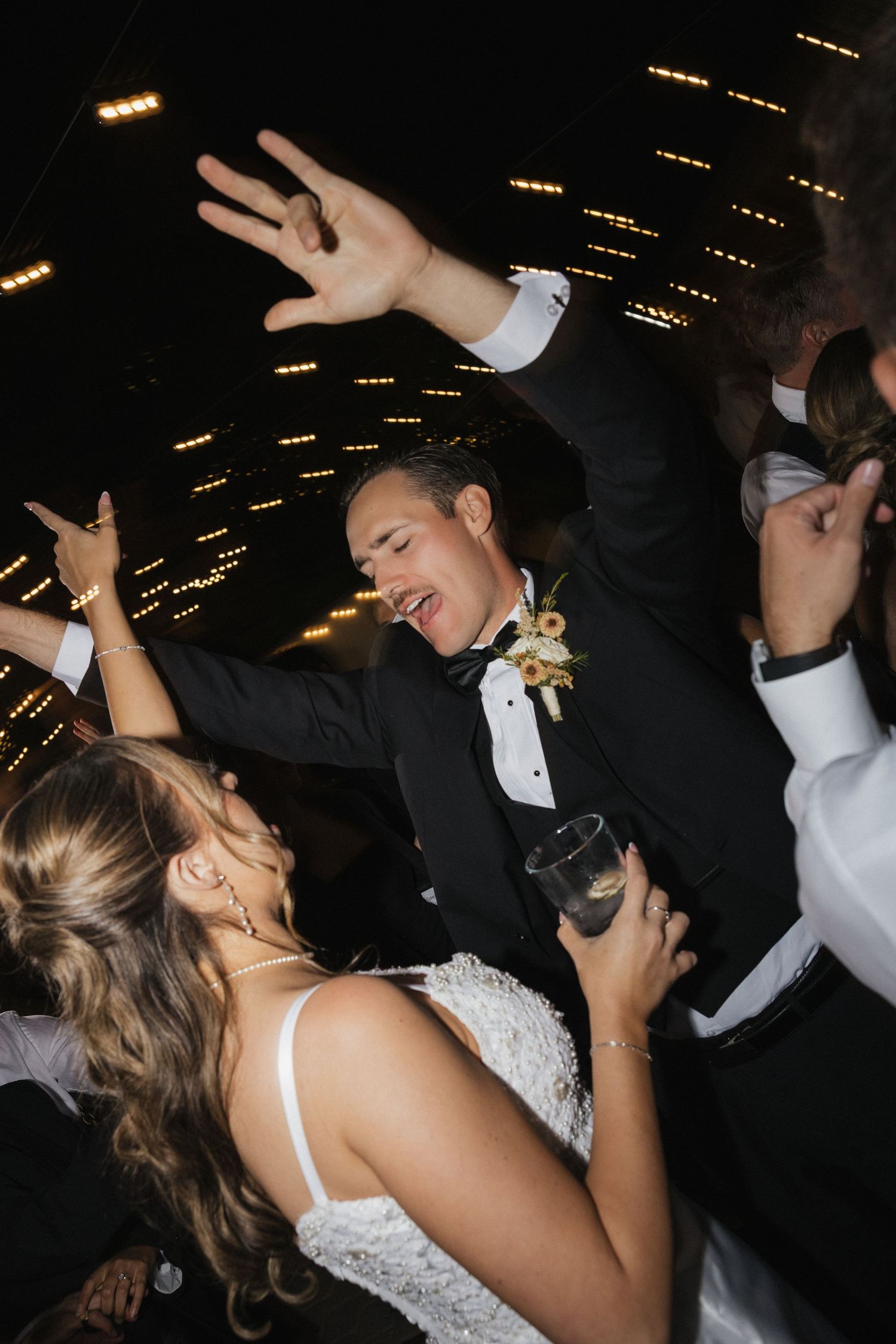 Wedding celebration on a dance floor with party lights and energetic dancing.