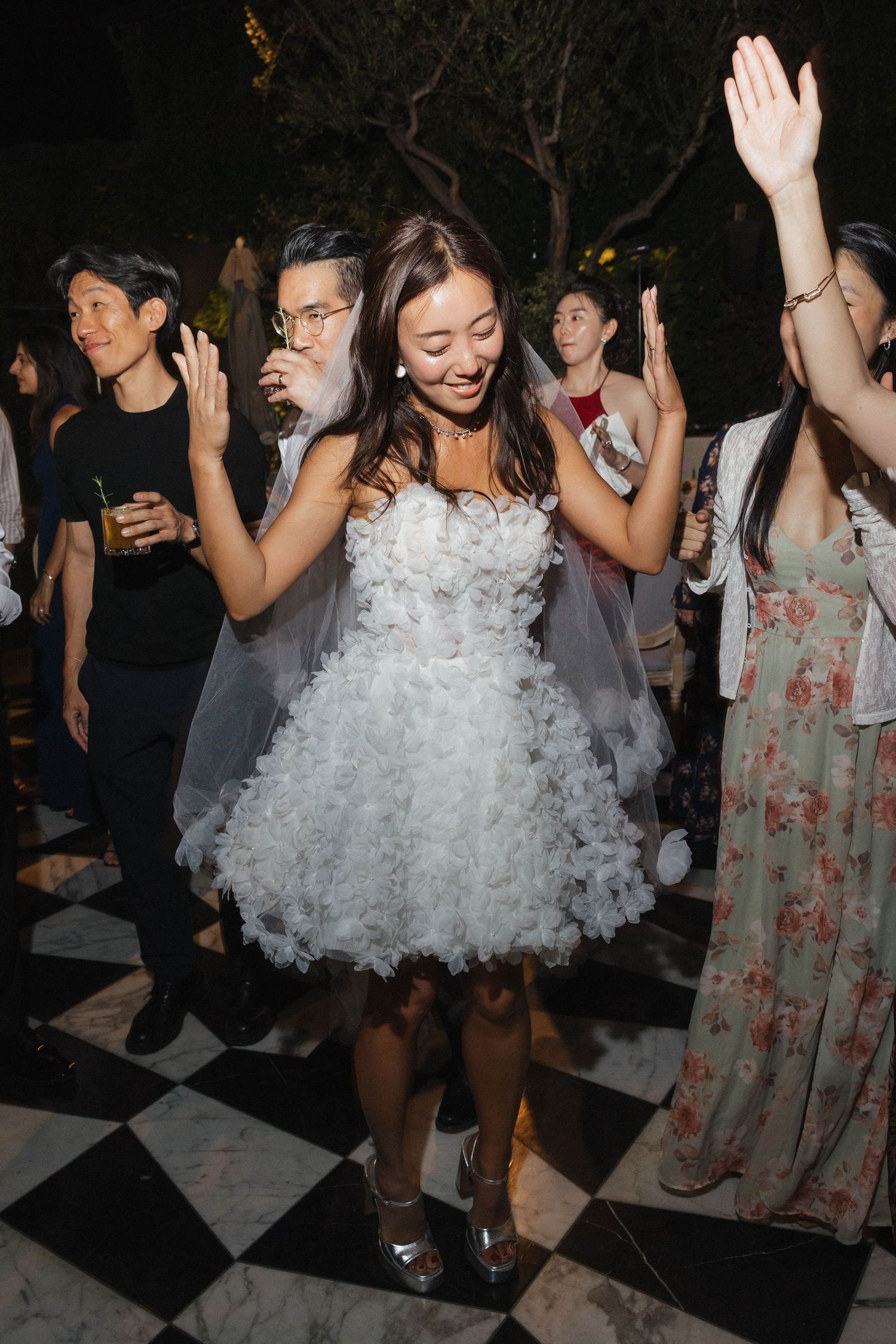 Wedding guests dancing on a checkered dance floor during an evening celebration.