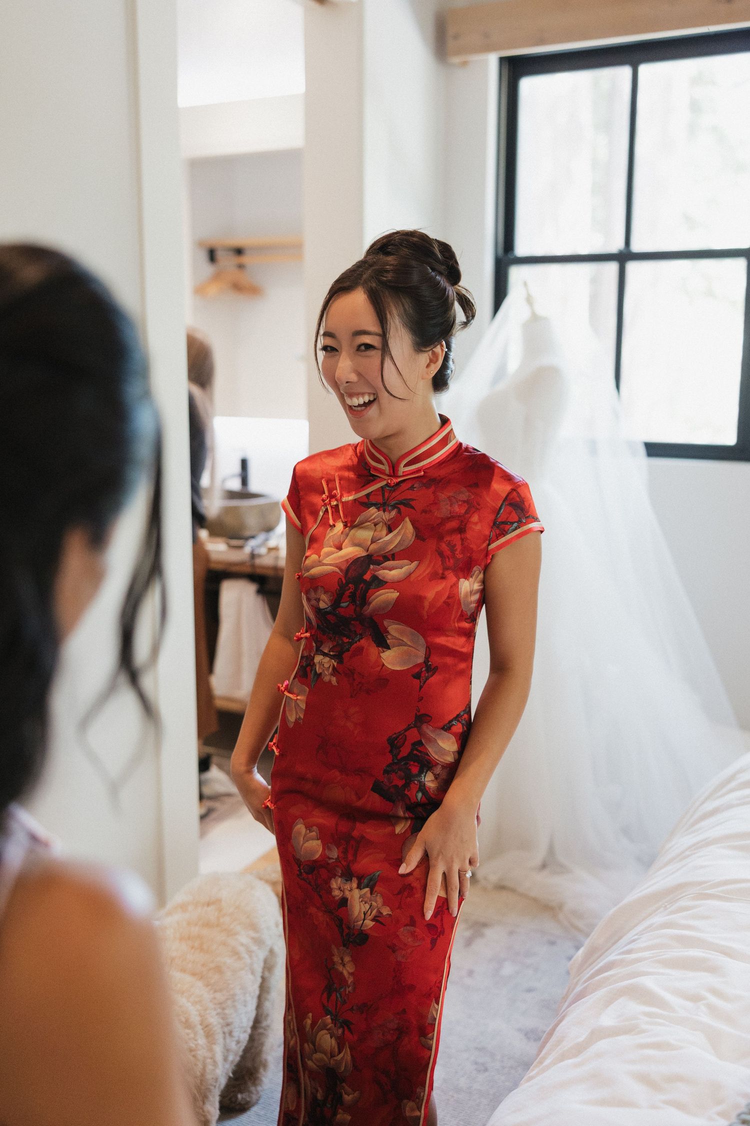 Person wearing a traditional red Chinese qipao dress in a bright indoor setting.