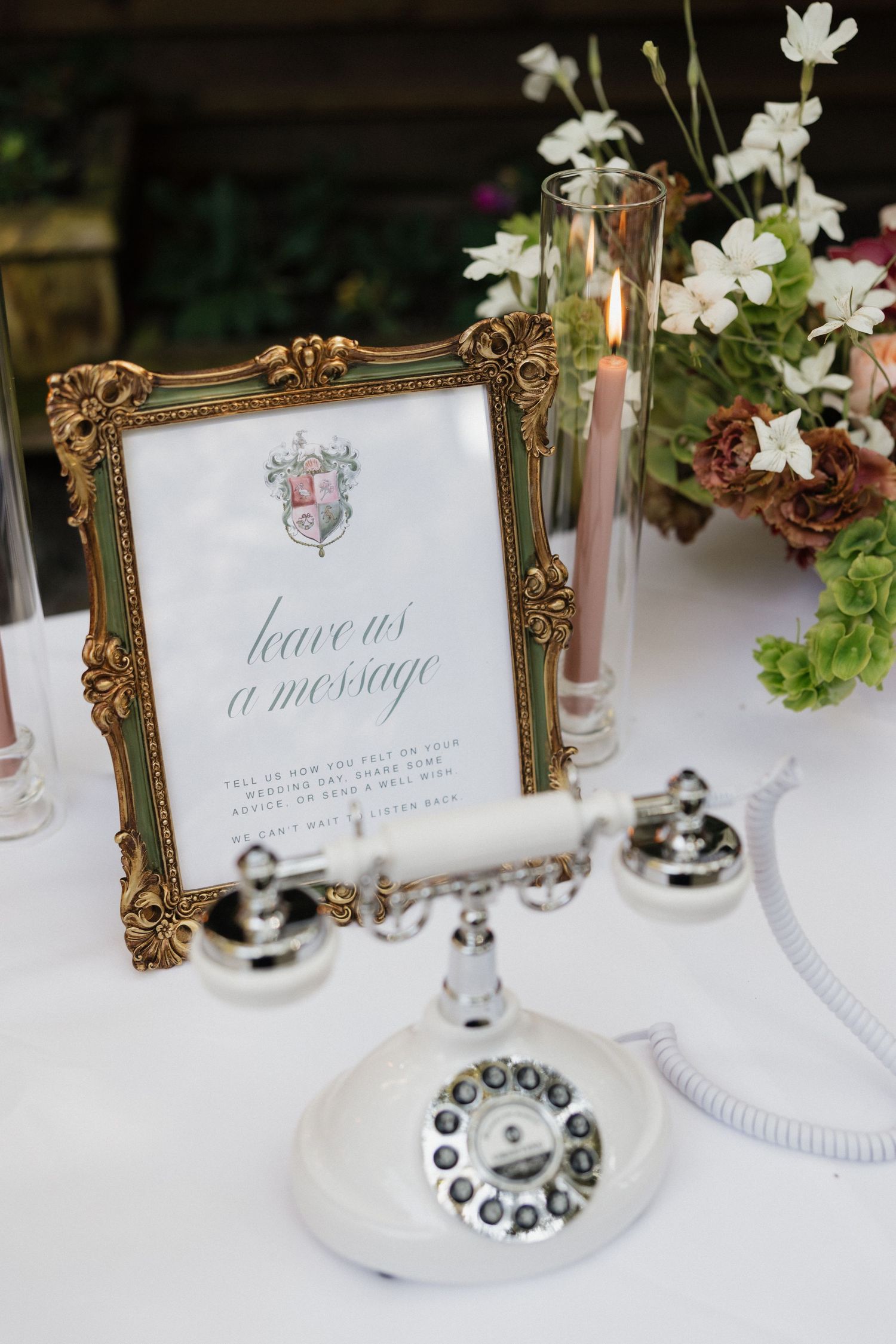 Vintage white rotary phone beside framed leave us a message wedding sign.
