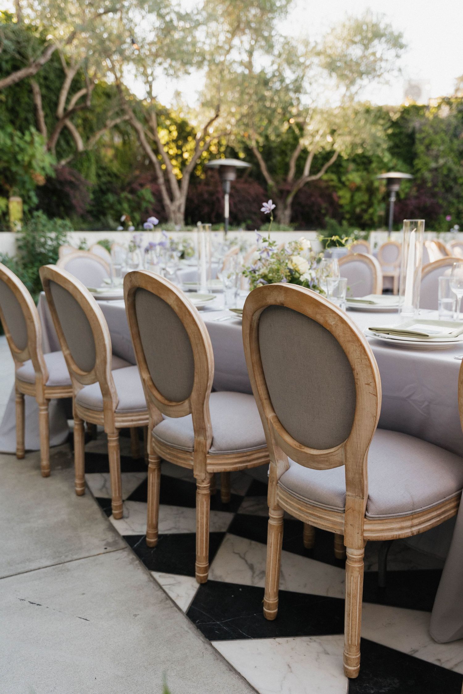 Row of vintage-style upholstered chairs arranged for an elegant outdoor wedding reception.