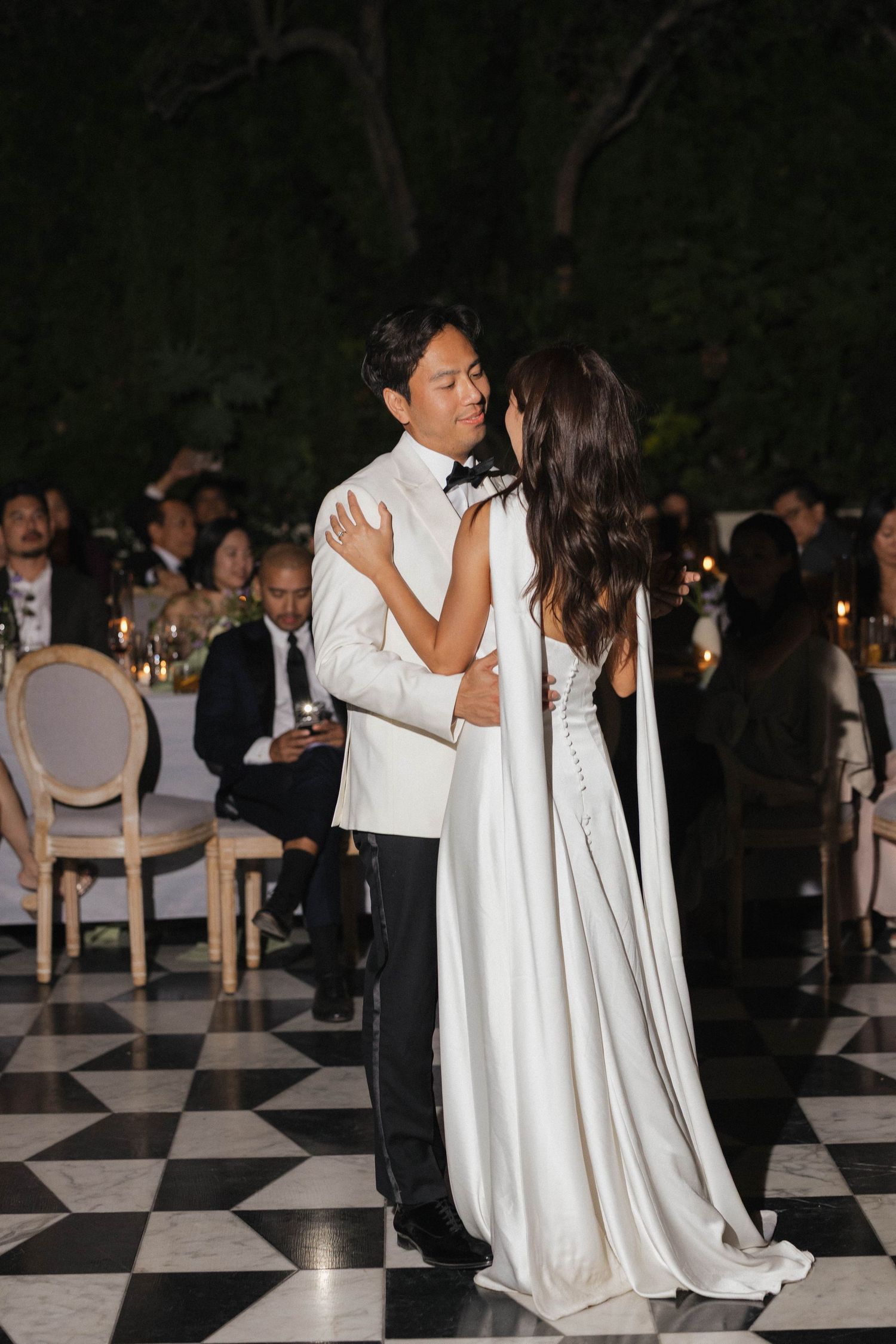 Couples dancing on a black and white checkered floor at an evening wedding reception.