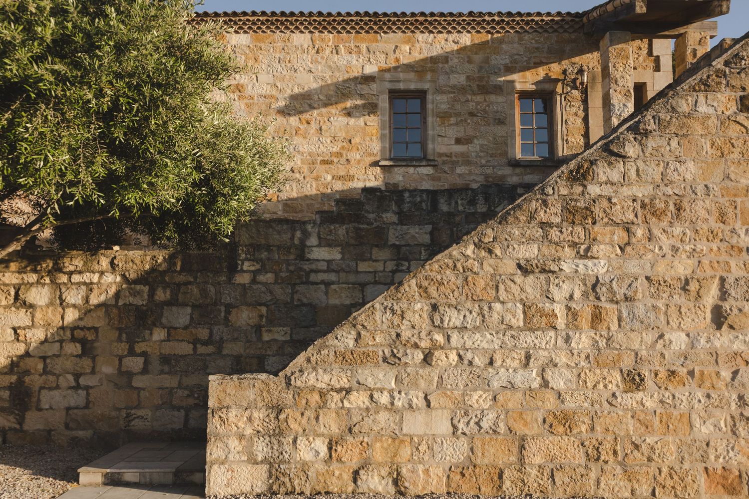 Ancient stone walls and architectural details of a historic building against blue sky.