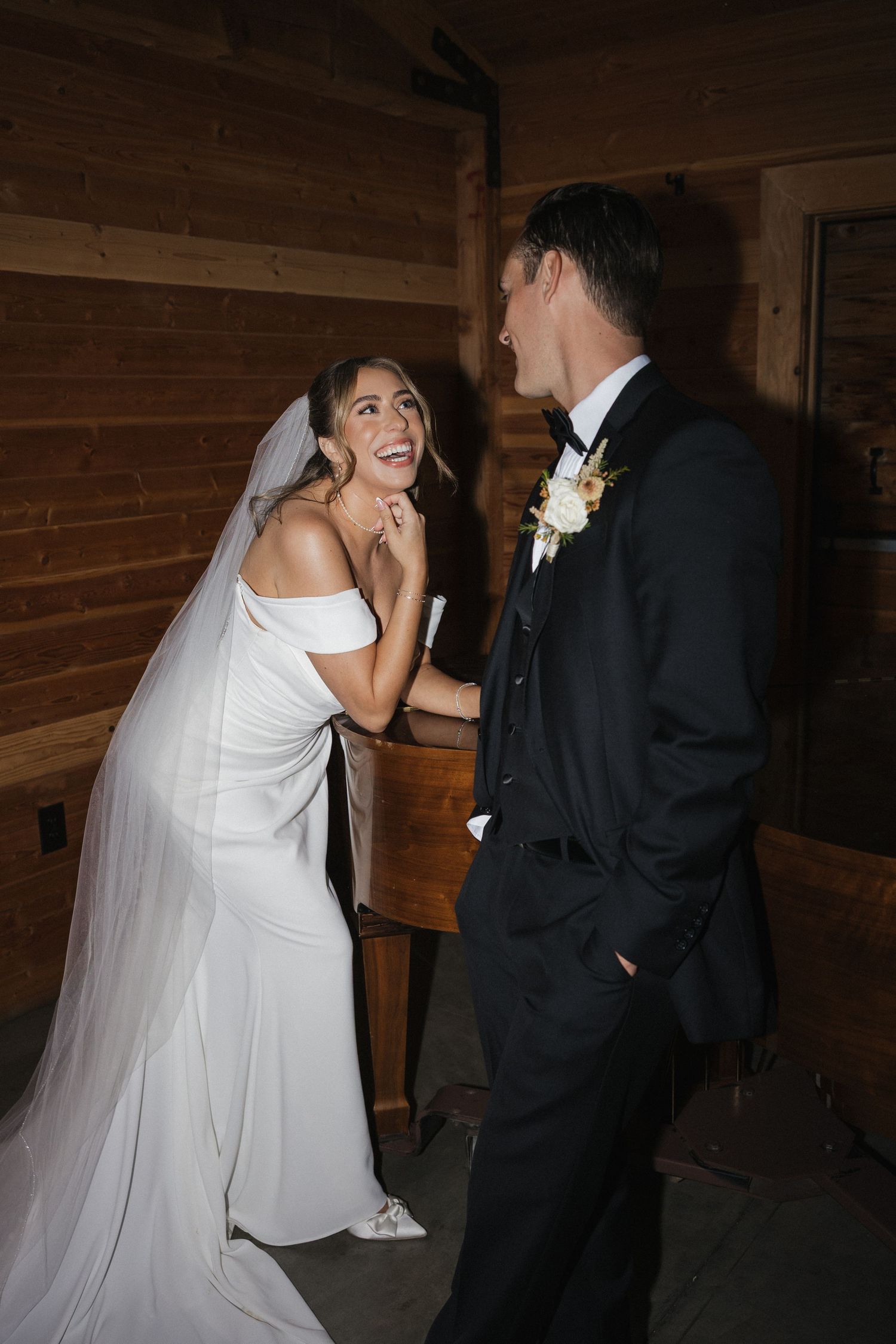 A couple shares joyful laughter during their first dance at an indoor wedding reception.