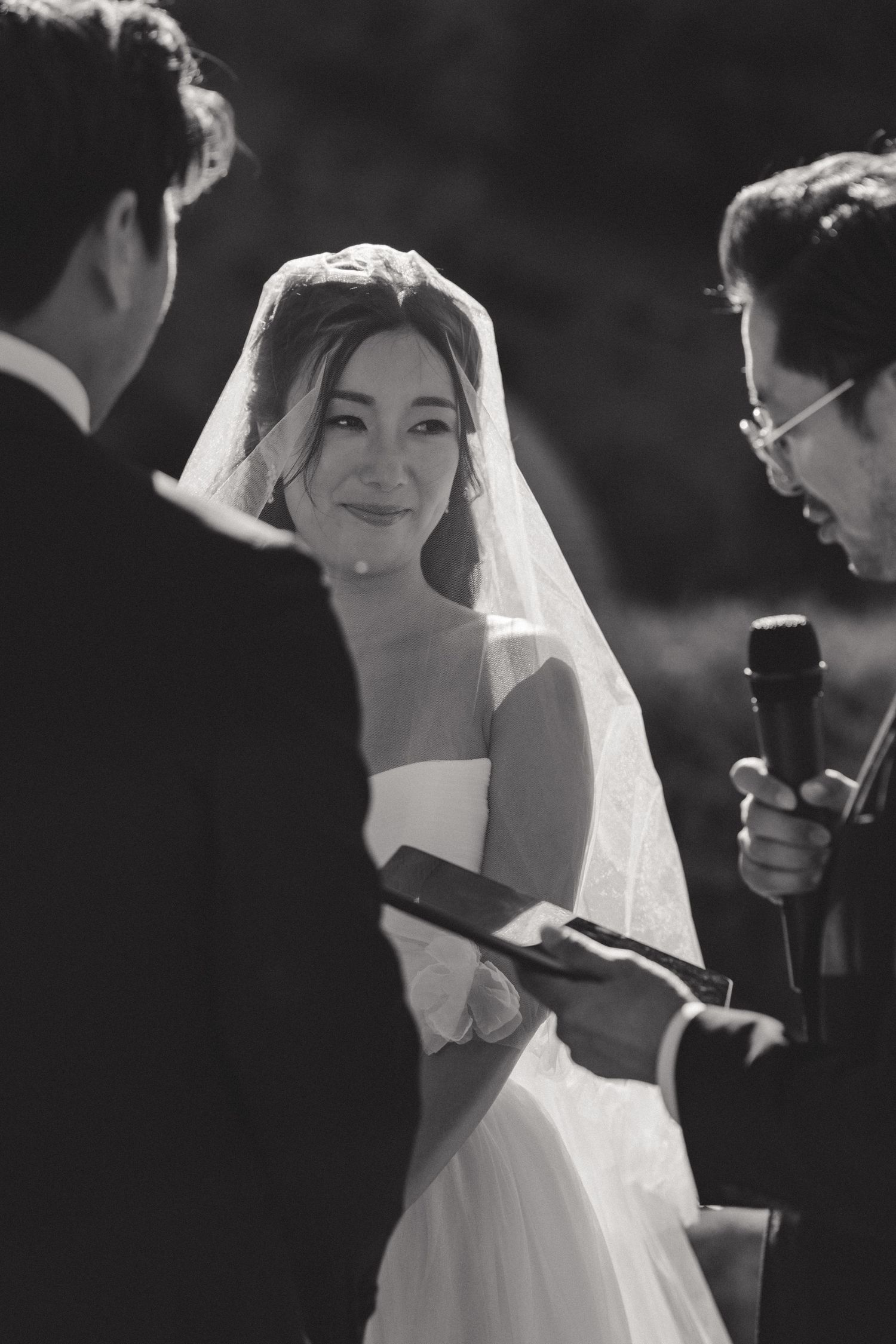 Black and white photo of a wedding ceremony moment with flowing veil.