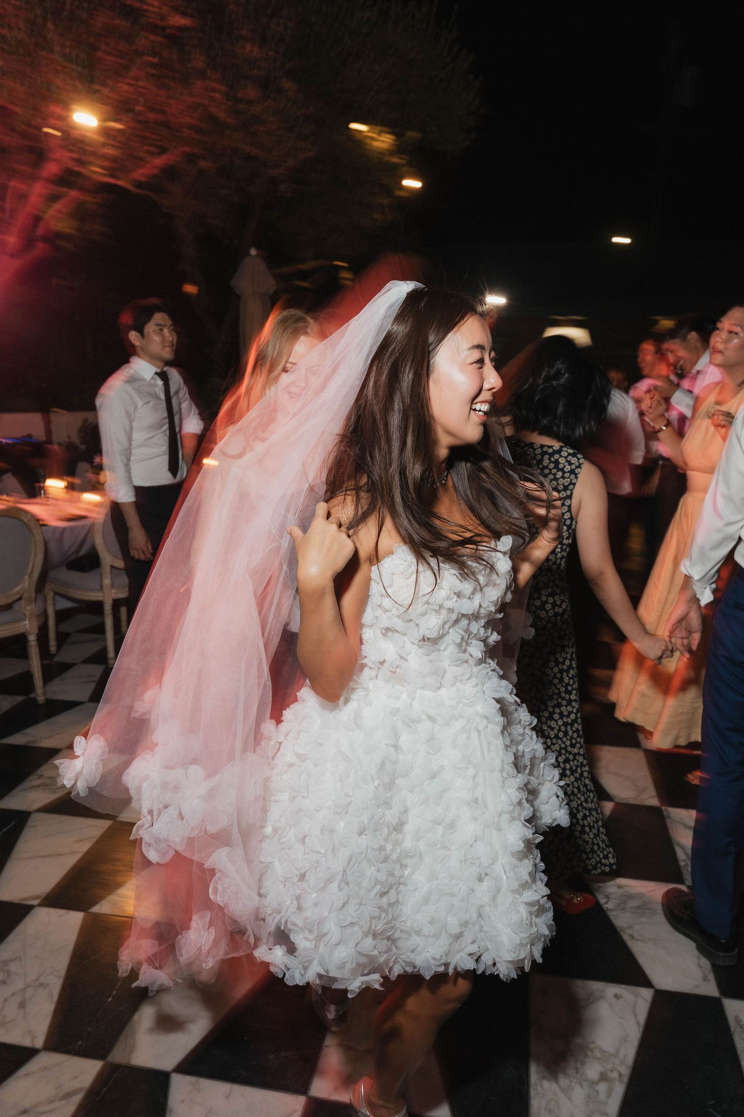 People dancing on a black and white checkered floor at a celebration event.