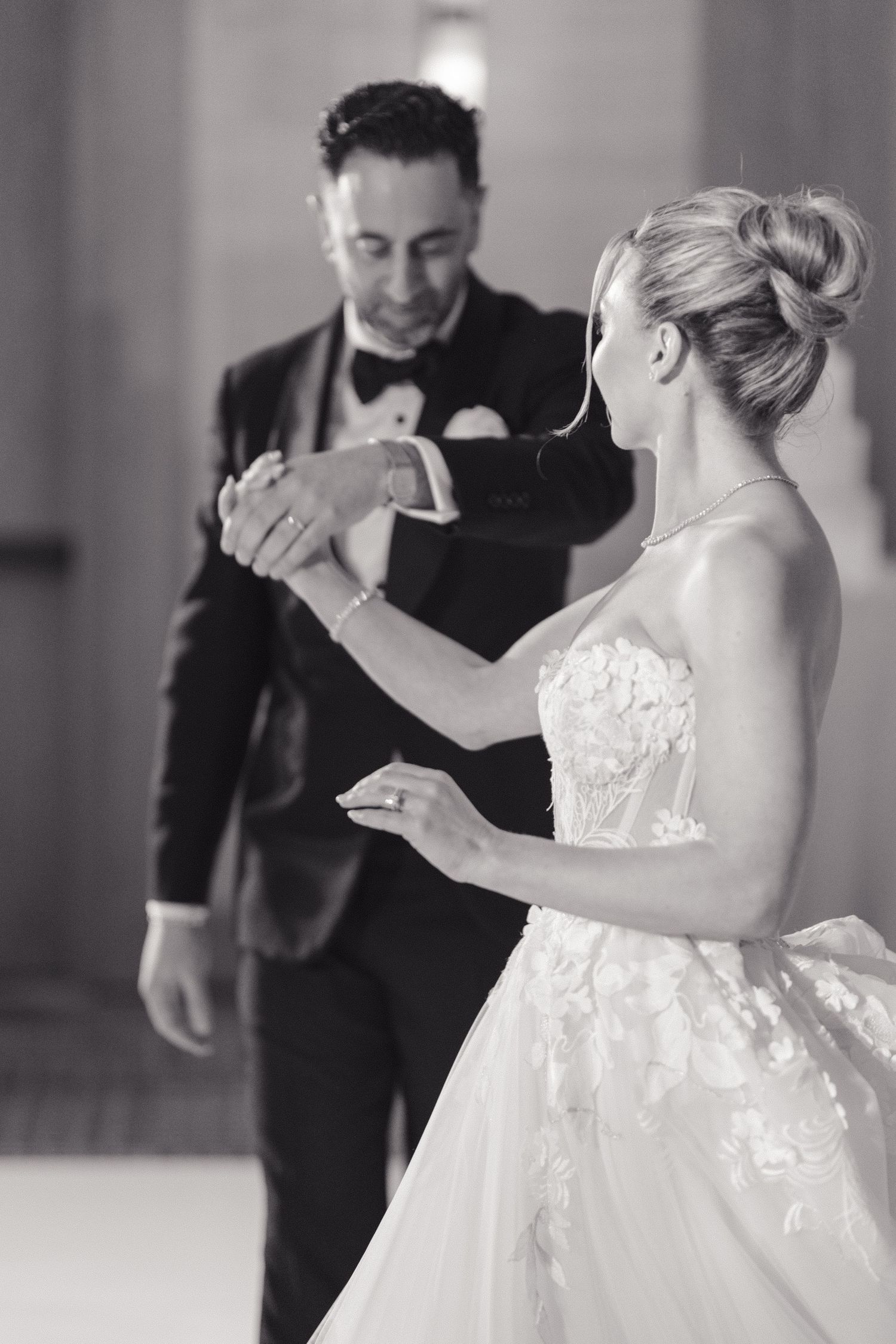 A bride in a white ball gown and groom in a tuxedo share their first dance at their wedding reception.