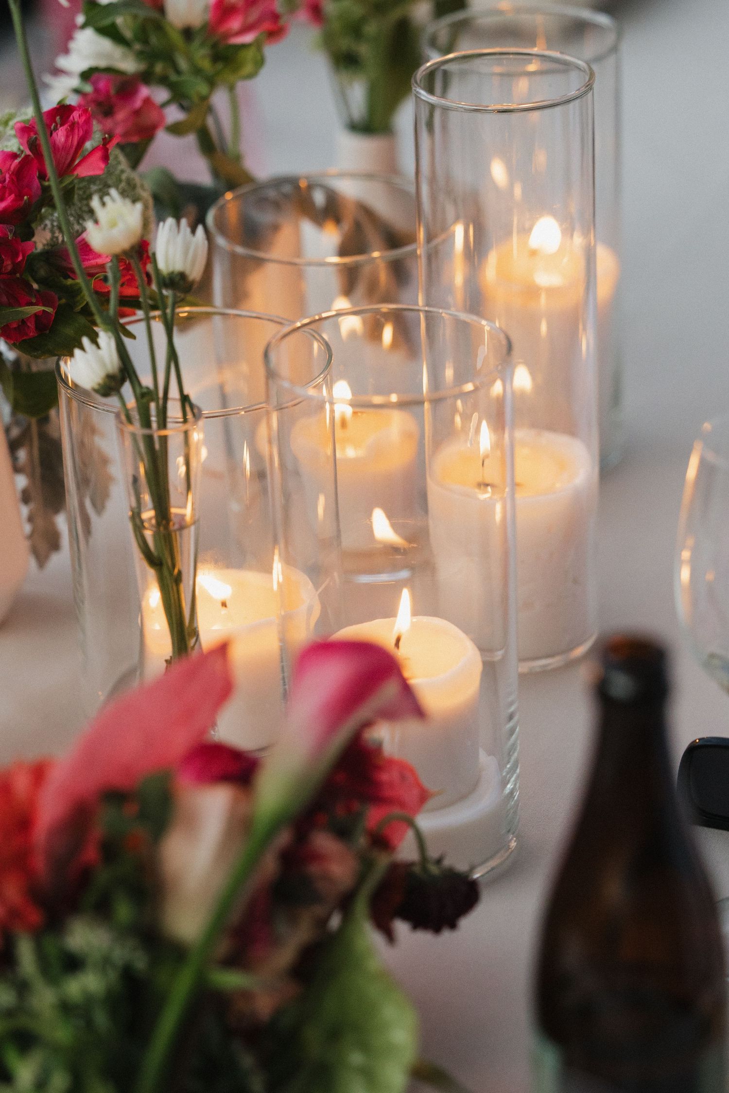 Elegant table setting with lit candles and pink floral arrangements at wedding reception.