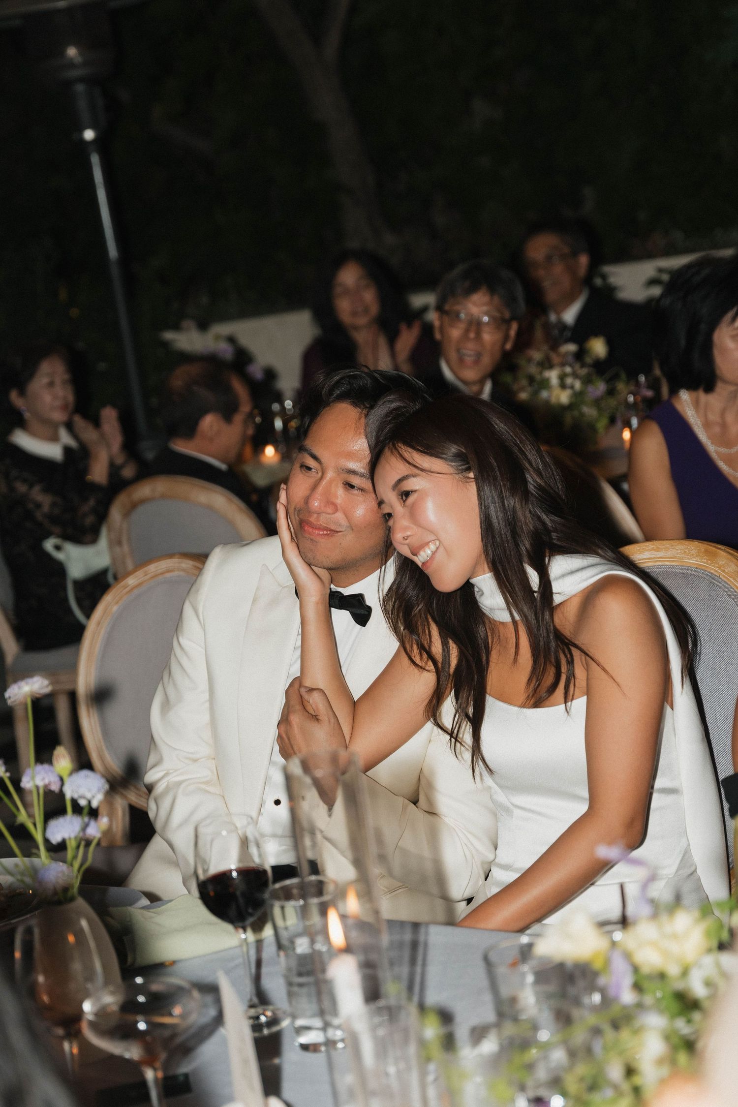 Wedding reception guests enjoying dinner and conversation at an evening celebration.
