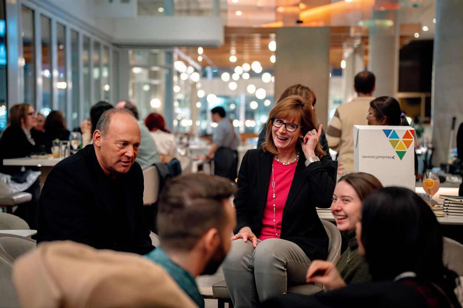 Guests mingling at modern evening wedding reception with glass walls | DC event photography