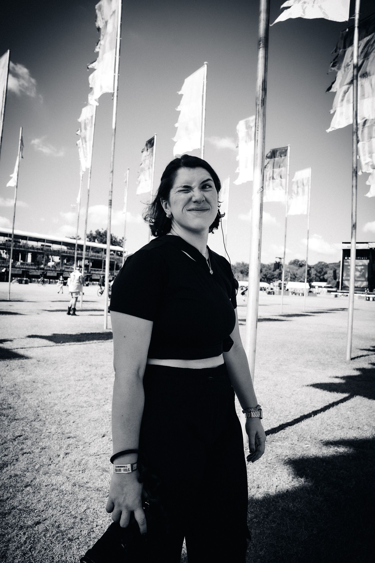Black and white photo showing person in dark clothing standing outdoors with white flags waving in the background.