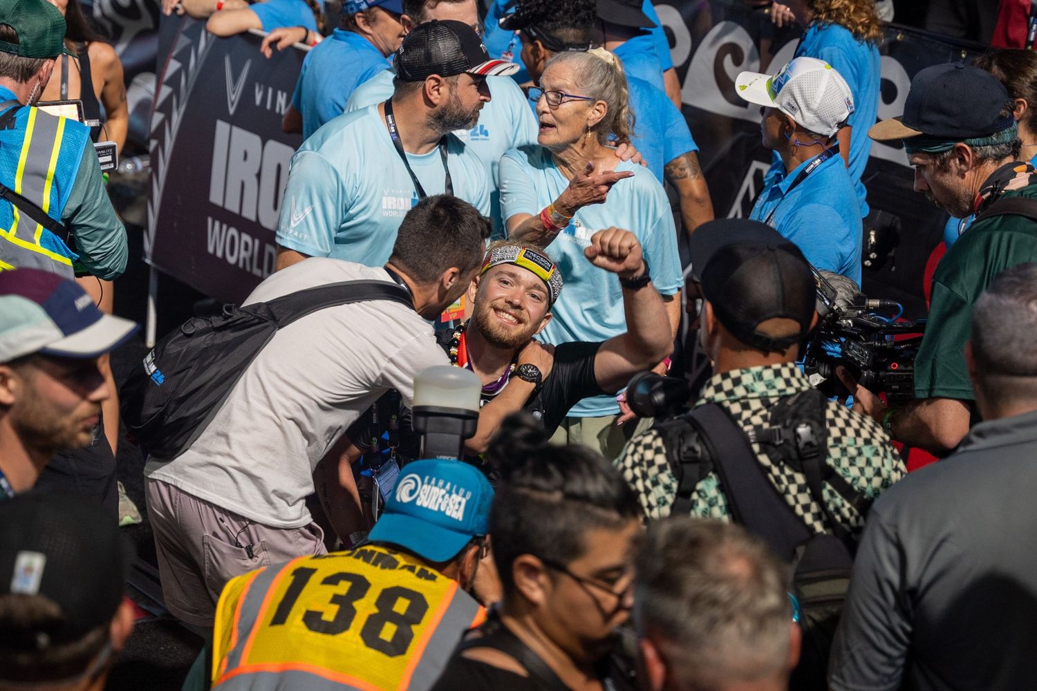 A crowd of spectators and race participants gather around number 138 at an outdoor sporting event.
