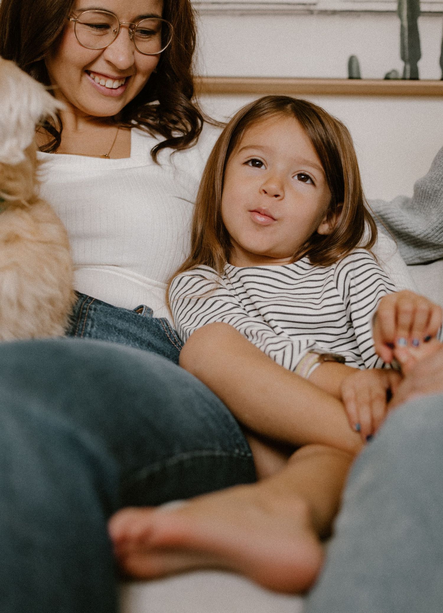 A young girl gets silly for the camera as her loving mom watches.