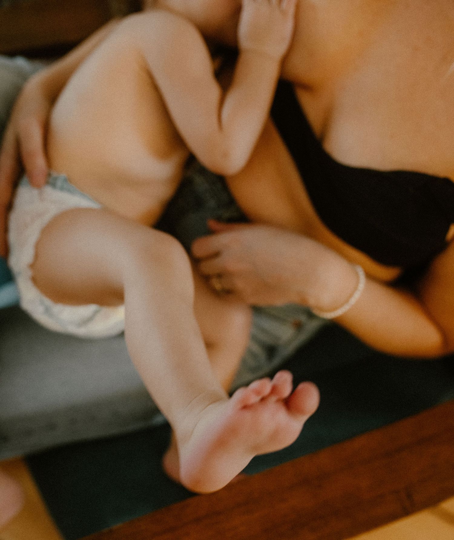 Close-up photo of baby feet and legs resting on couch with parent nursing.