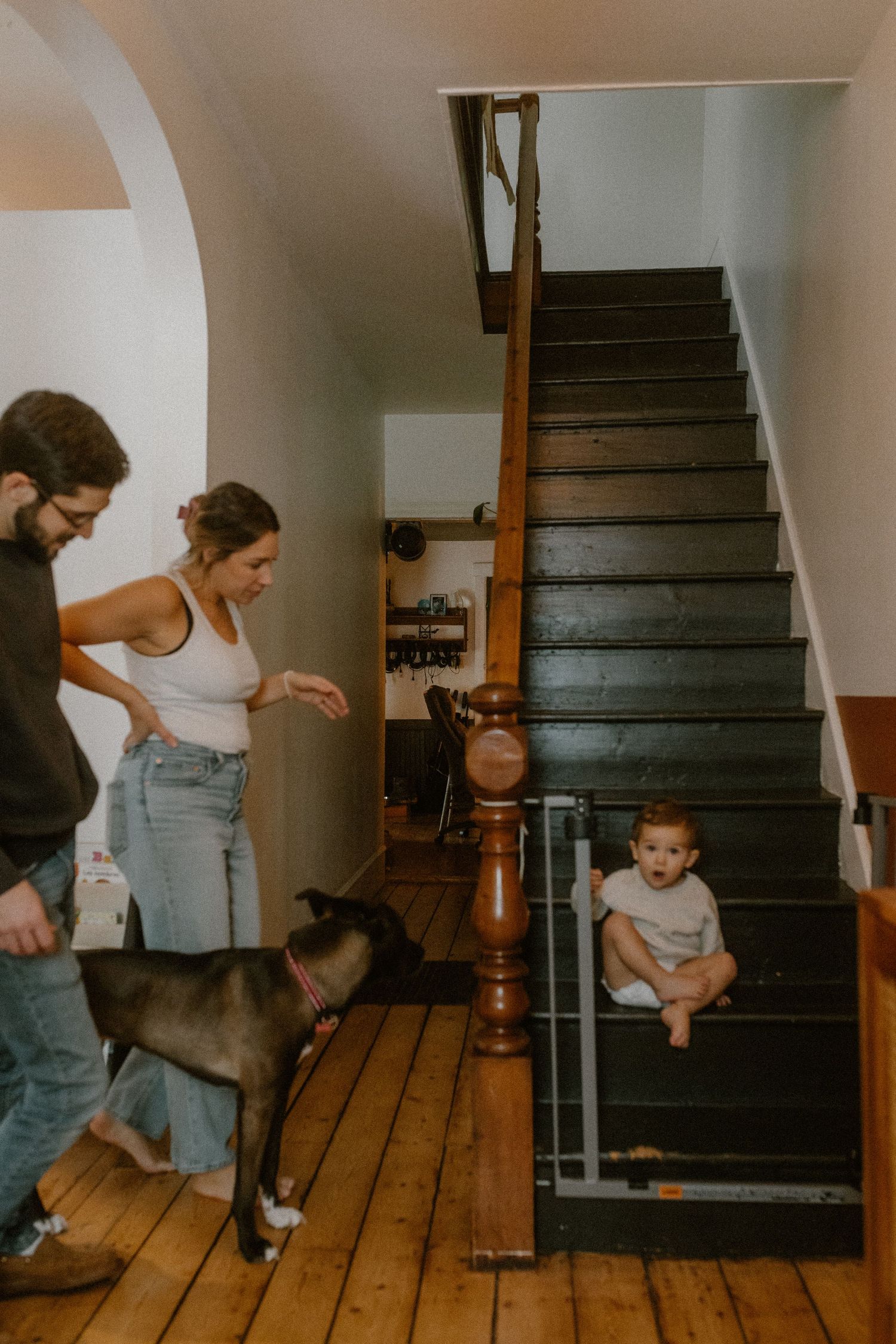 Family and dog gather near wooden stairs while a child sits on the steps.