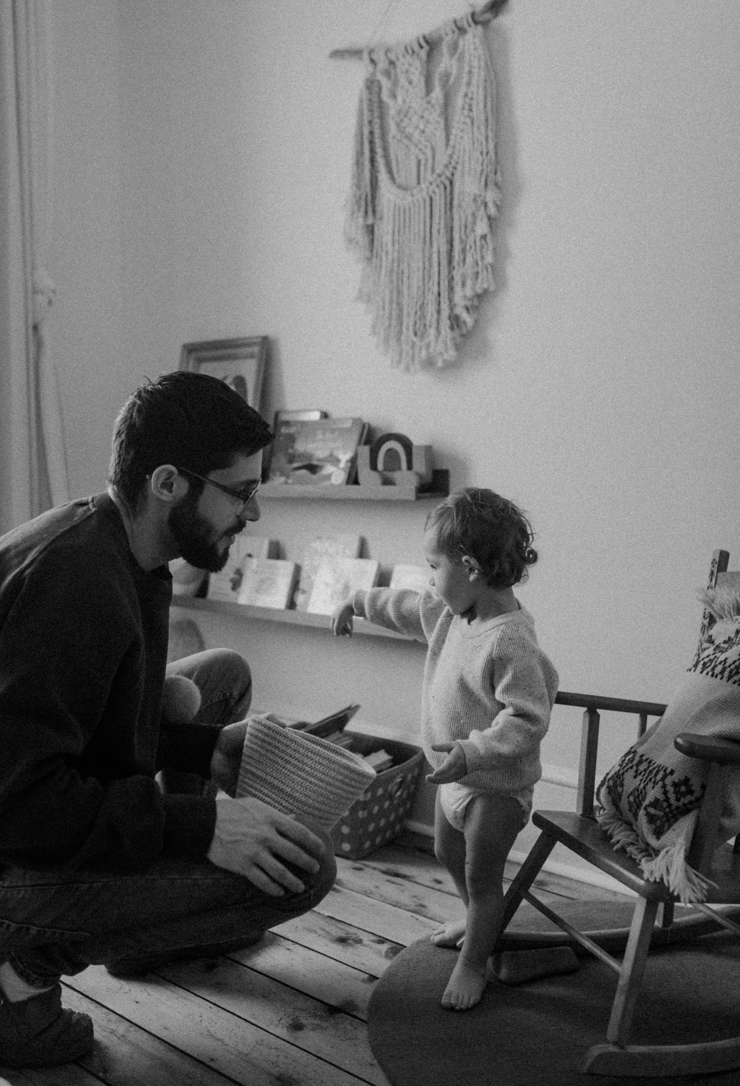 A black and white photo showing a tender moment between two people in a decorated nursery room.