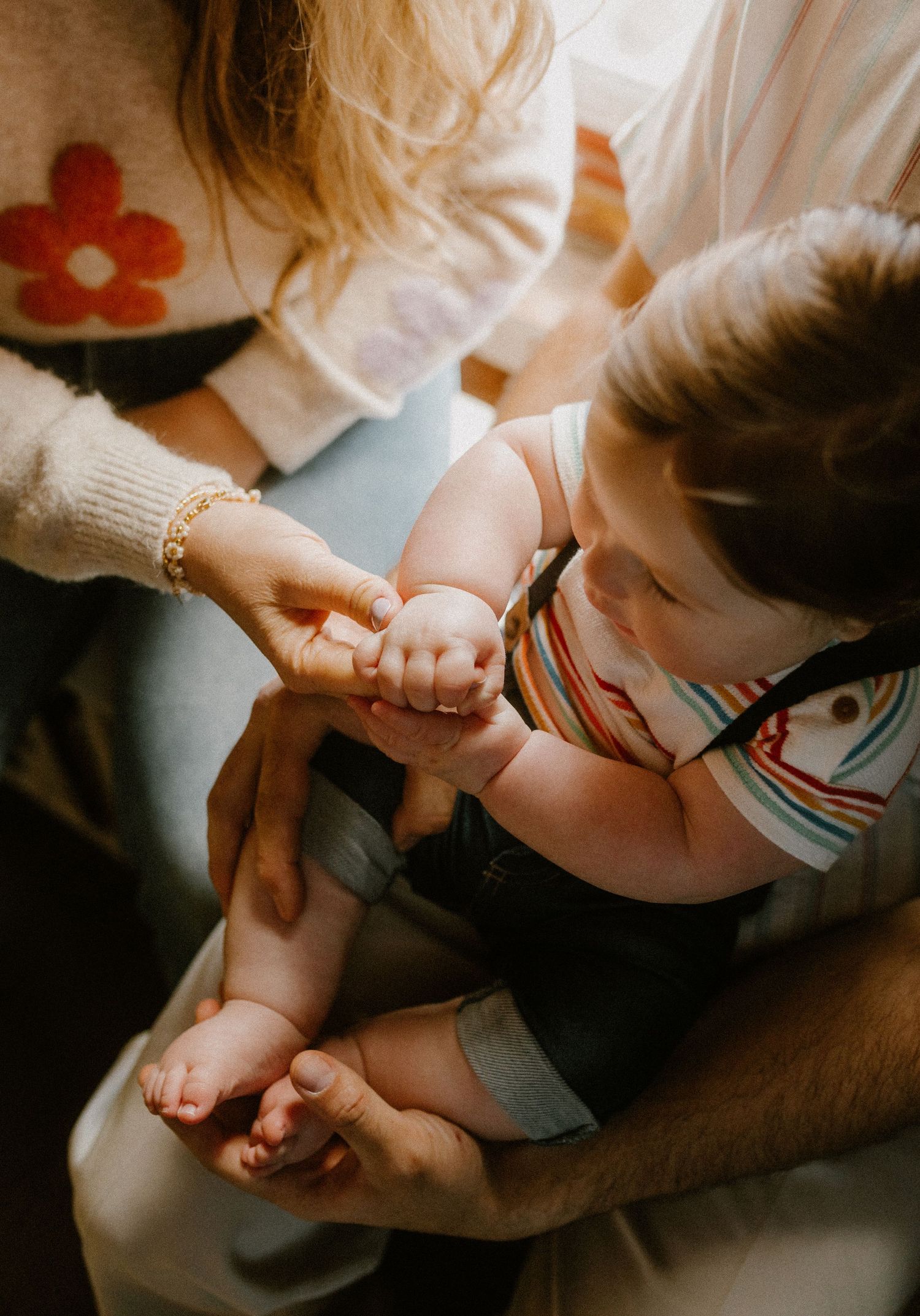 Close-up view of hands holding and connecting during an intimate family moment in soft lighting.