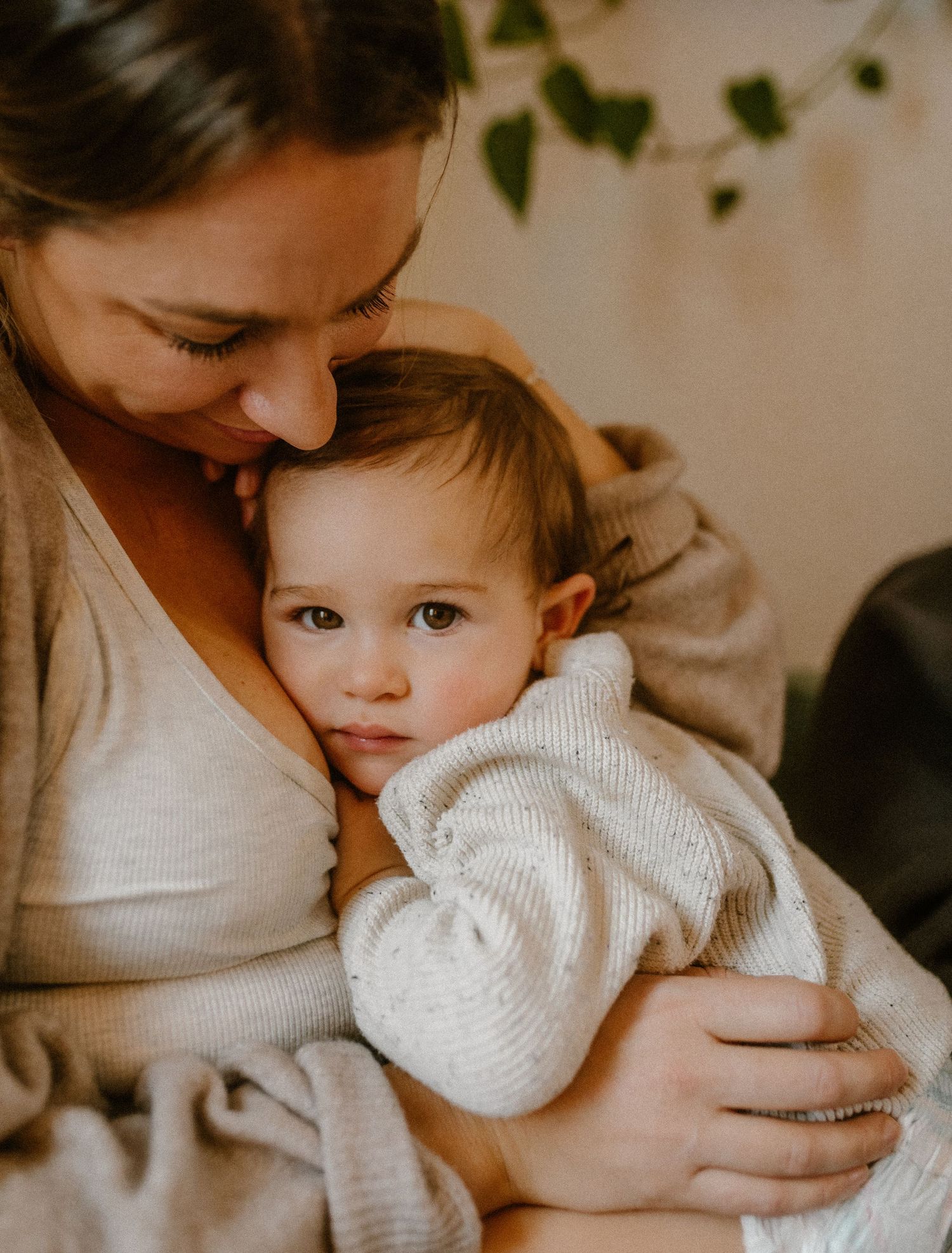 Tender moment captured in warm lighting with trailing plants in background.