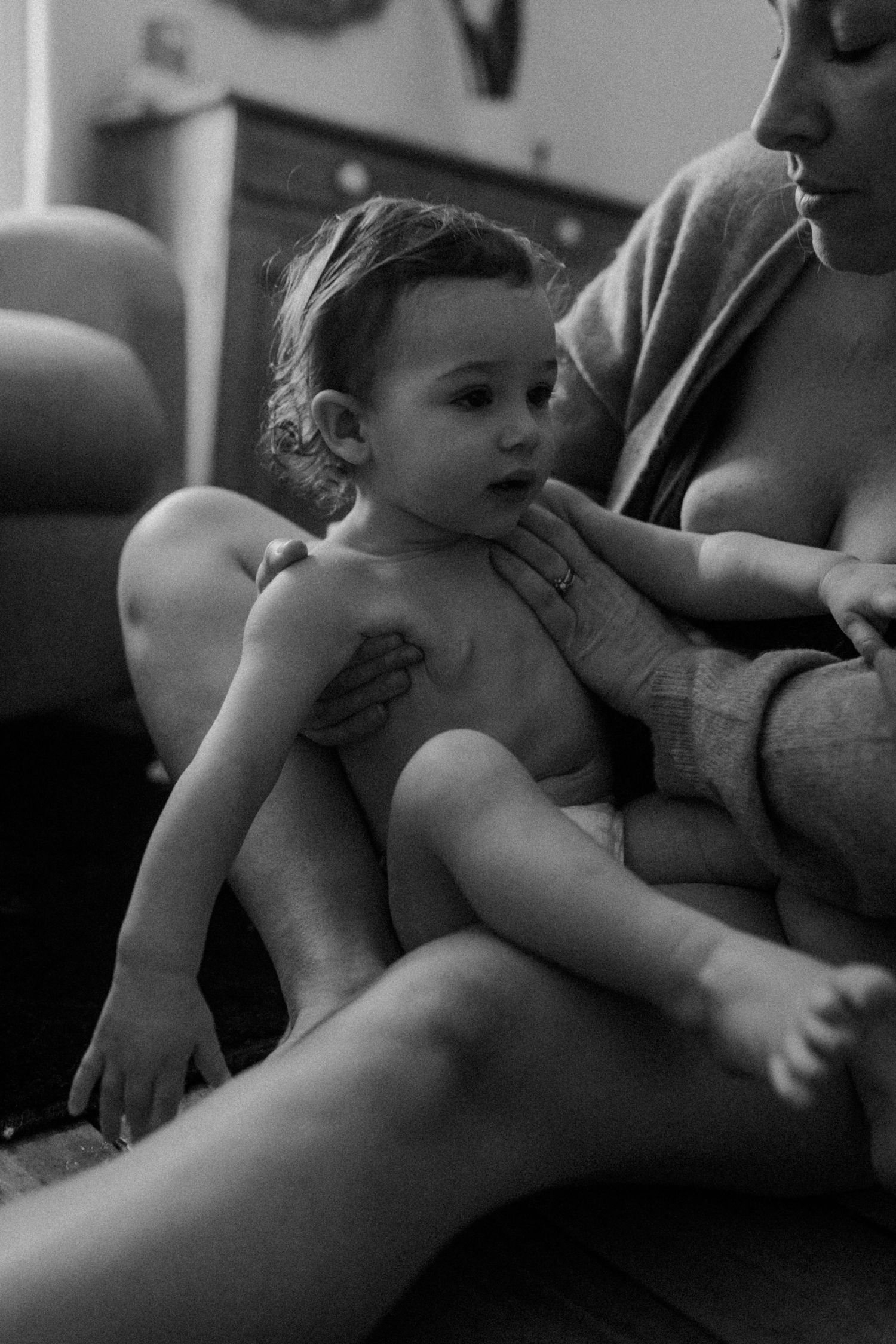 Intimate black and white photograph of a small child resting in her mother's arms.