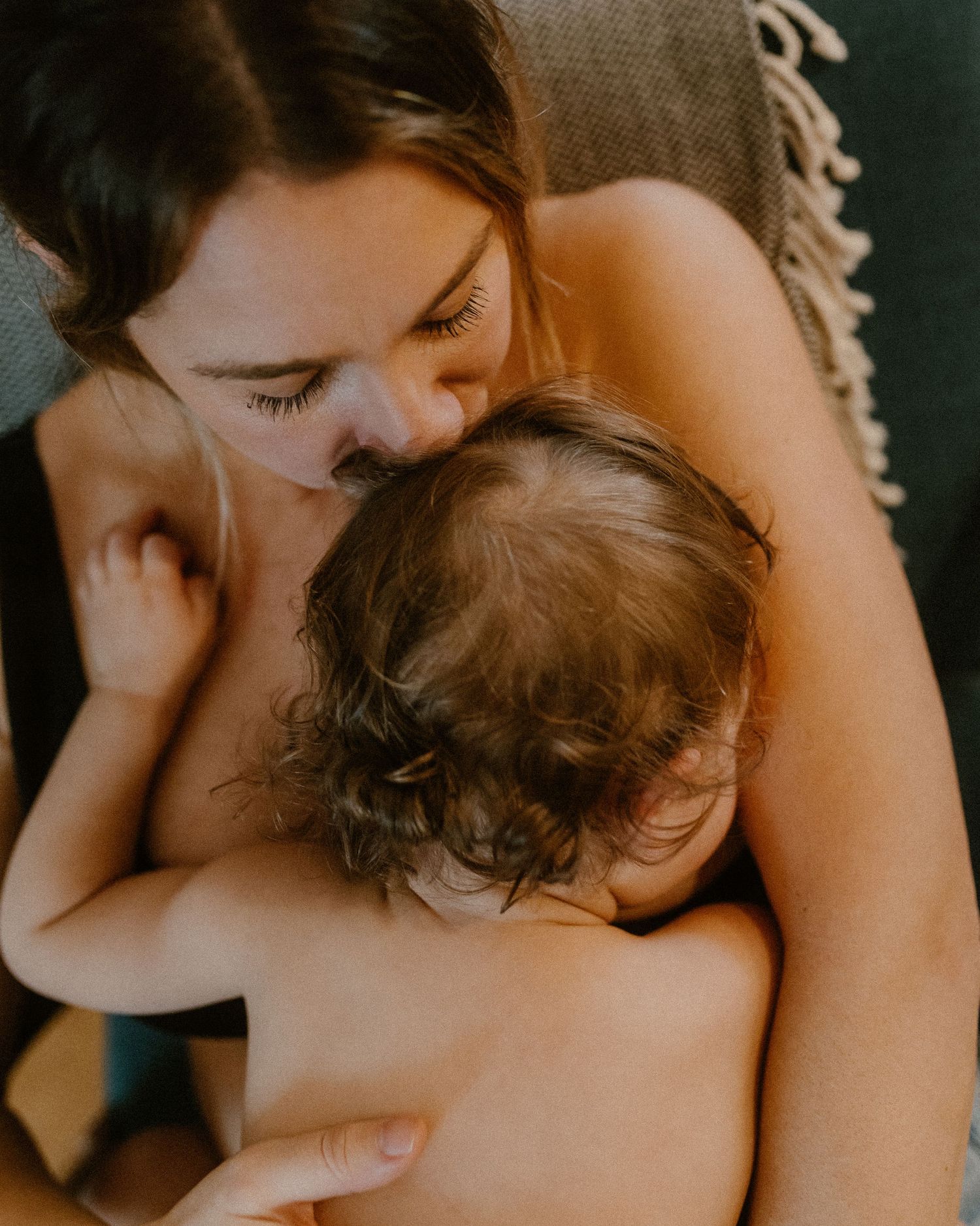 Tender moment of maternal bonding as parent cuddles with baby in intimate close-up photograph.