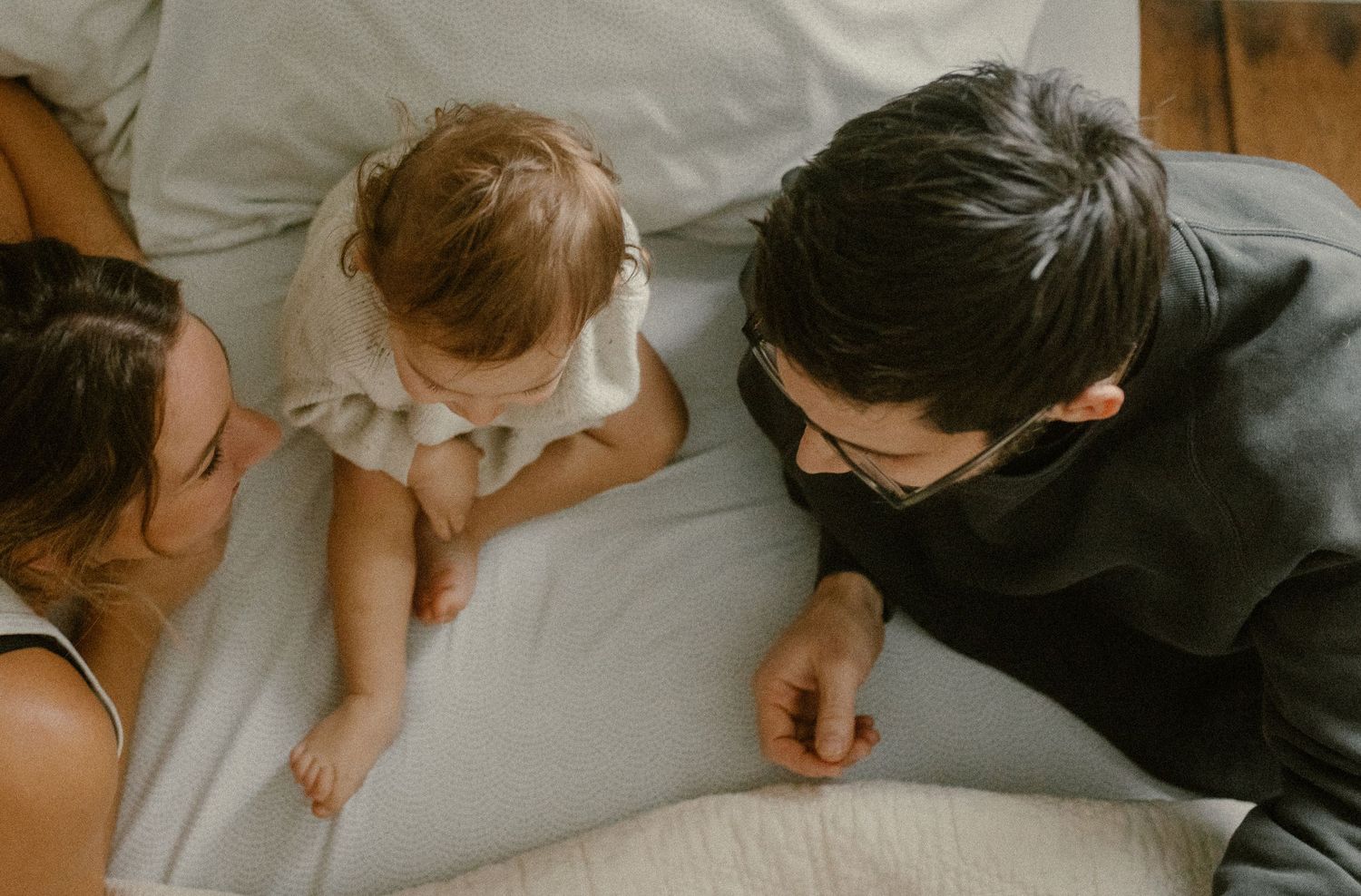 Candid lifestyle photo showing tender family interactions on white bedding.