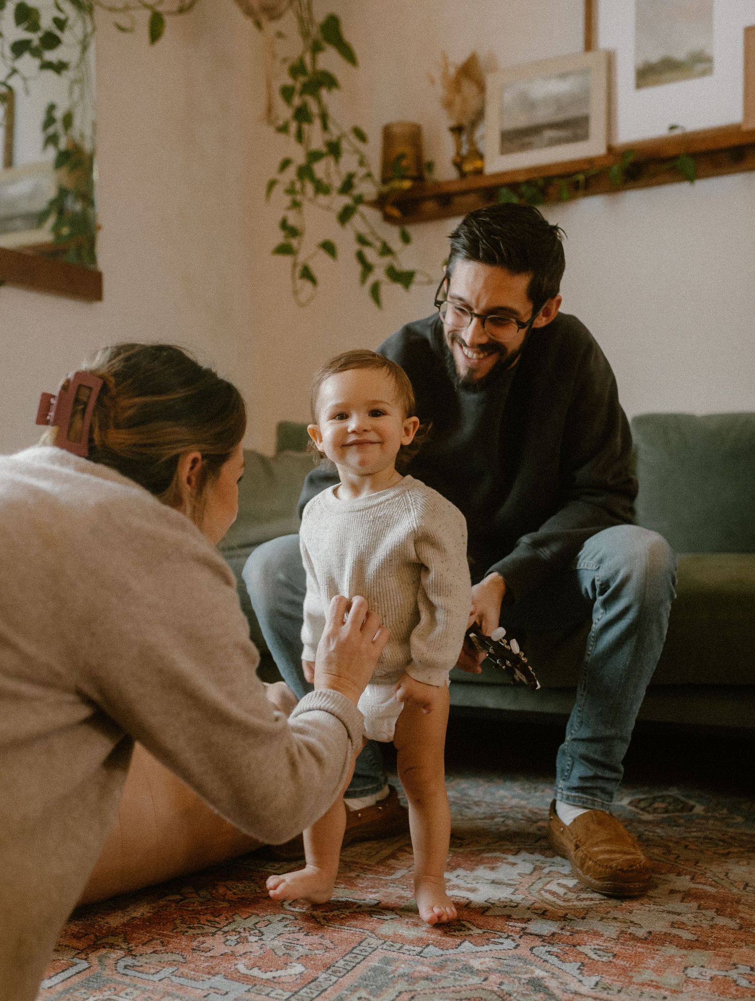Candid family interaction in a living room with vintage decor and trailing plants.