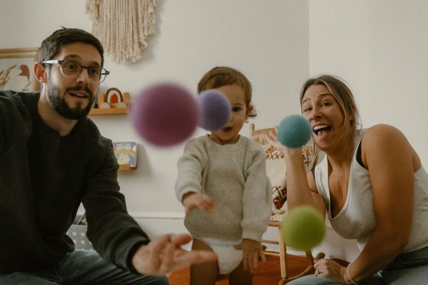Family playing together with colorful floating balloons in a bright living room interior.