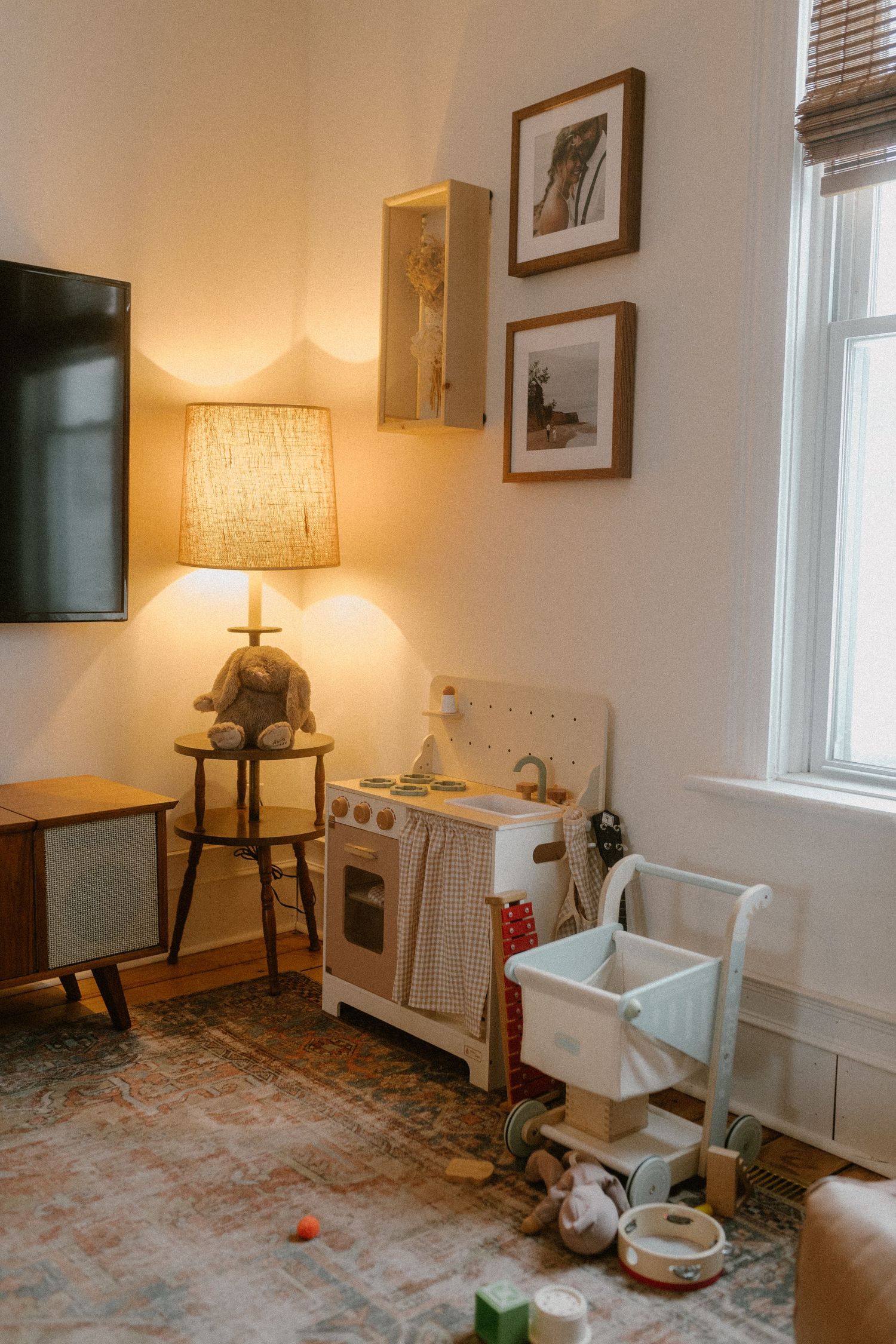 A cozy children's play area with toy kitchen, frames, and warm lighting.