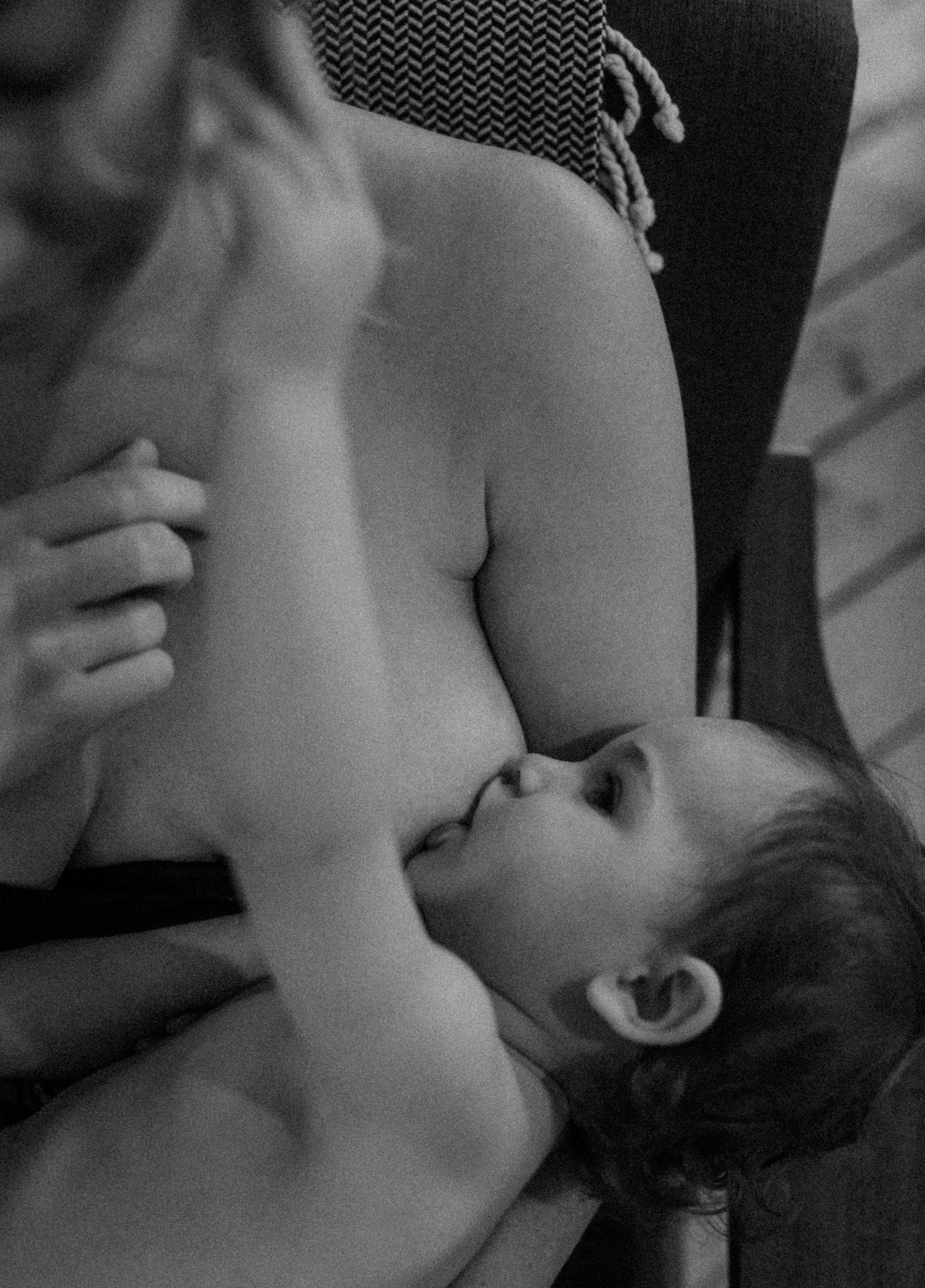 Artistic black and white intimate portrait capturing tender breastfeeding moment between mother and baby.