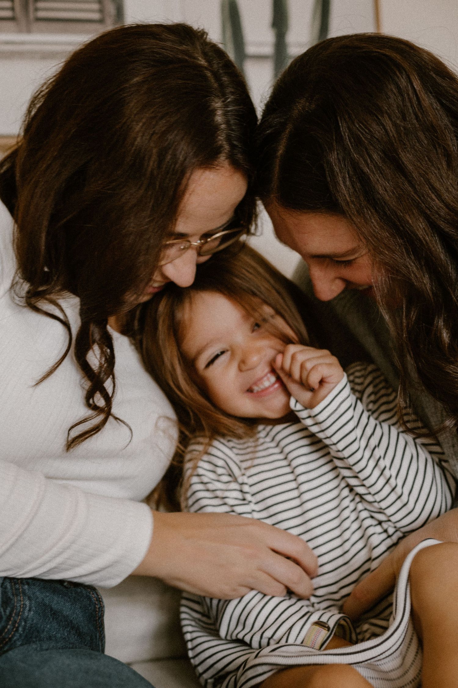 A joyful moment of shared laughter and cuddles on a couch.