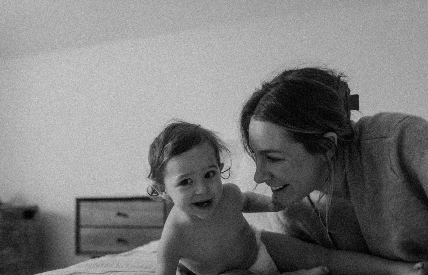 A tender black and white photograph of a parent and baby sharing a joyful moment together.