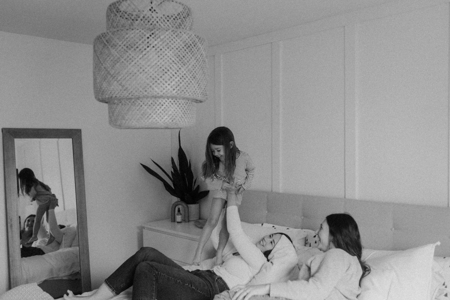 Black and white interior shot of a family playing in a bedroom with modern decor.