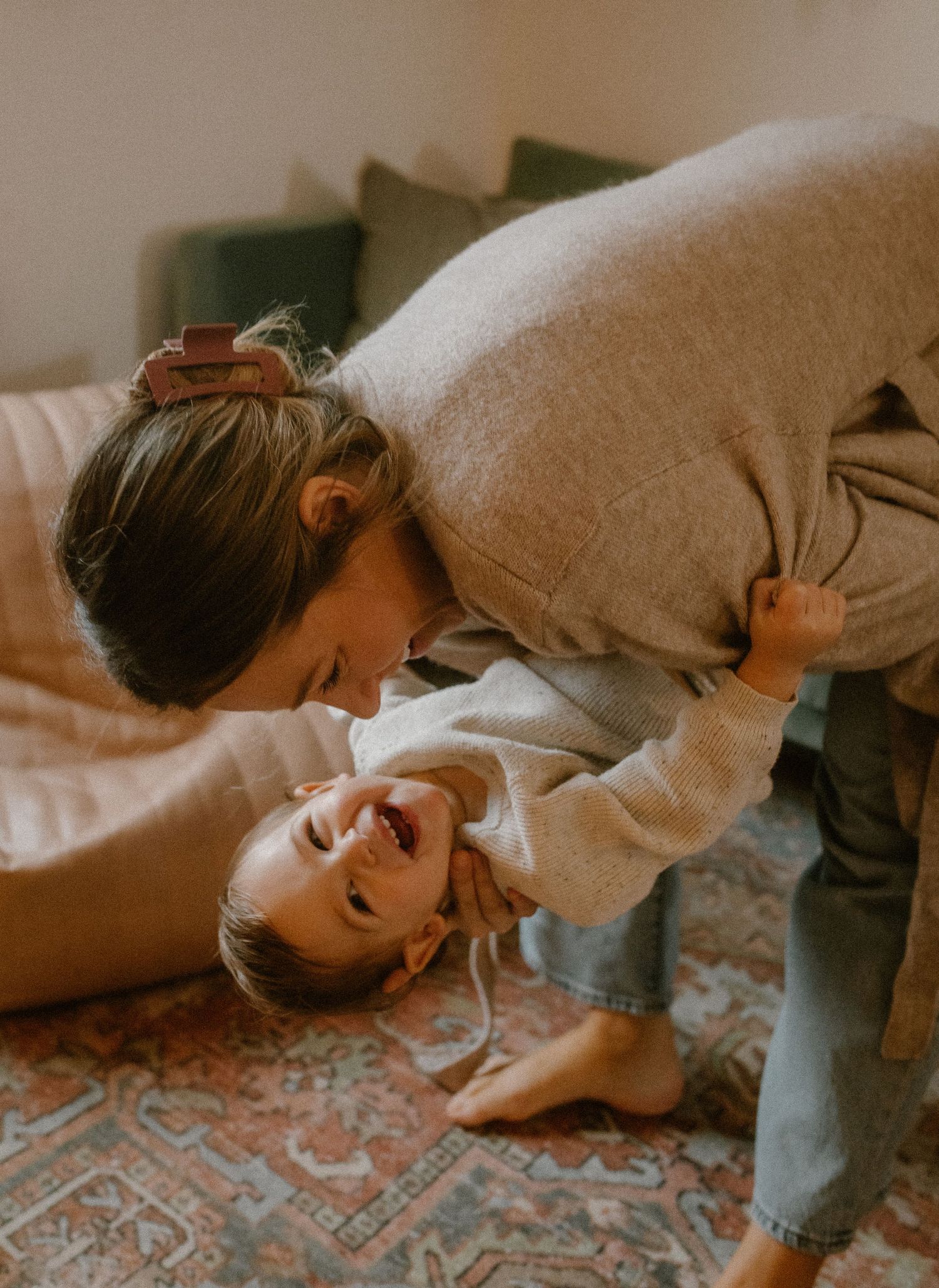 Candid interaction between two people on a decorative rug in warm lighting.